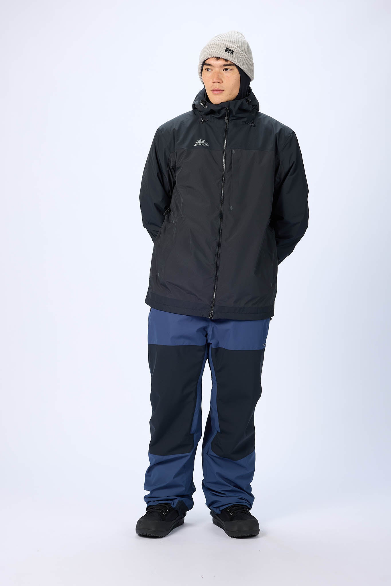 Person wearing a black jacket and blue pants on a white background