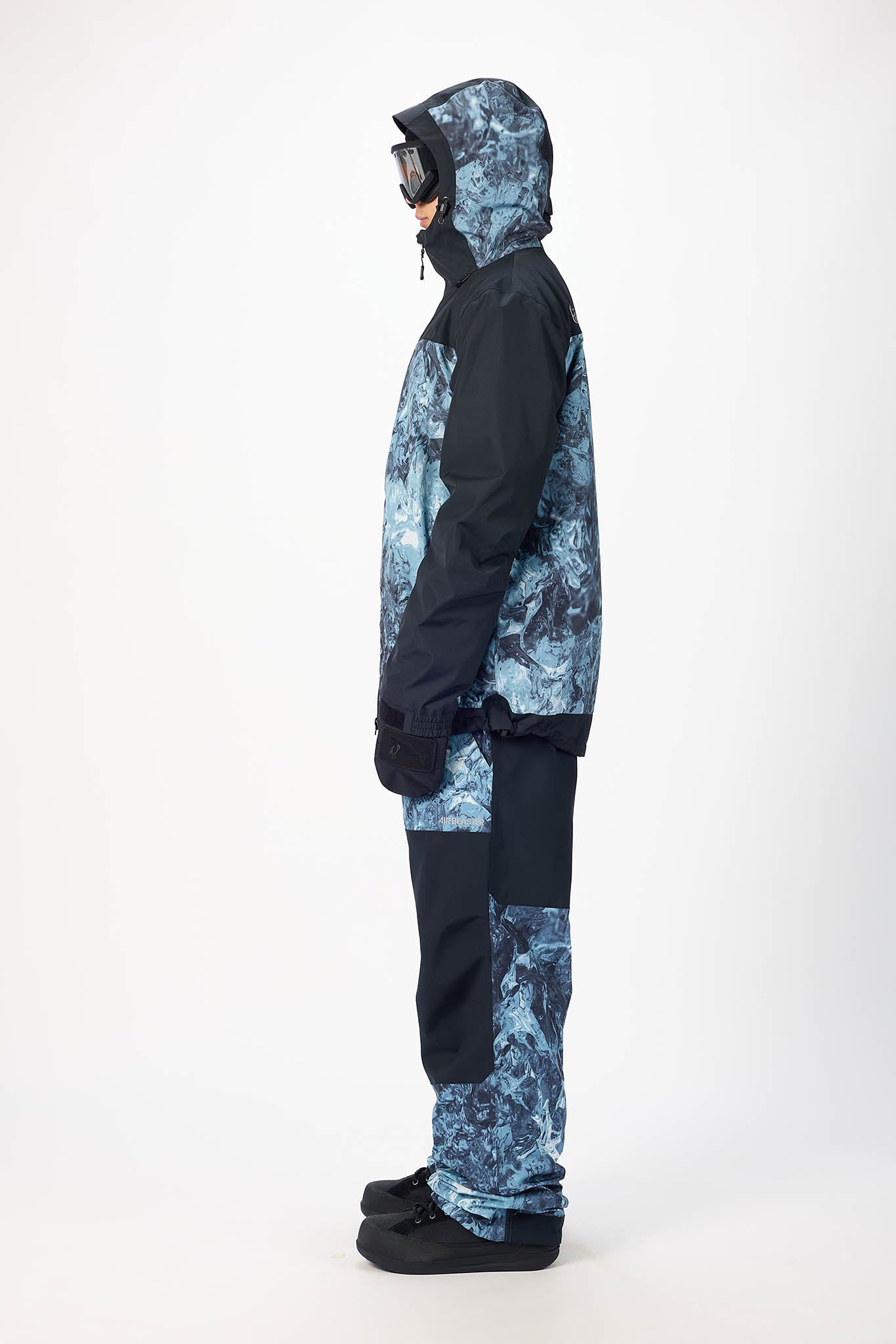 Person wearing a blue and black camouflage snowsuit on a white background