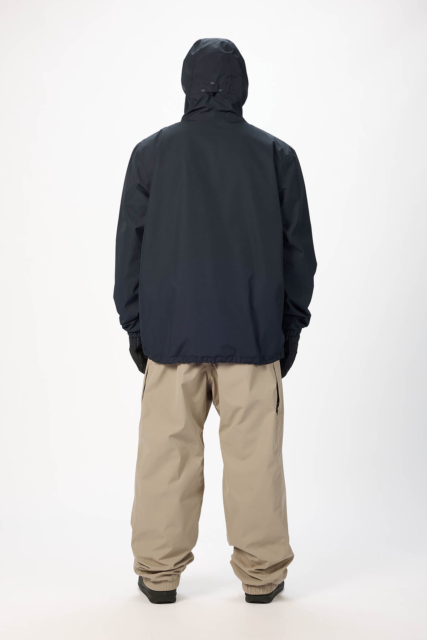 Person wearing a black jacket and beige pants on a white background