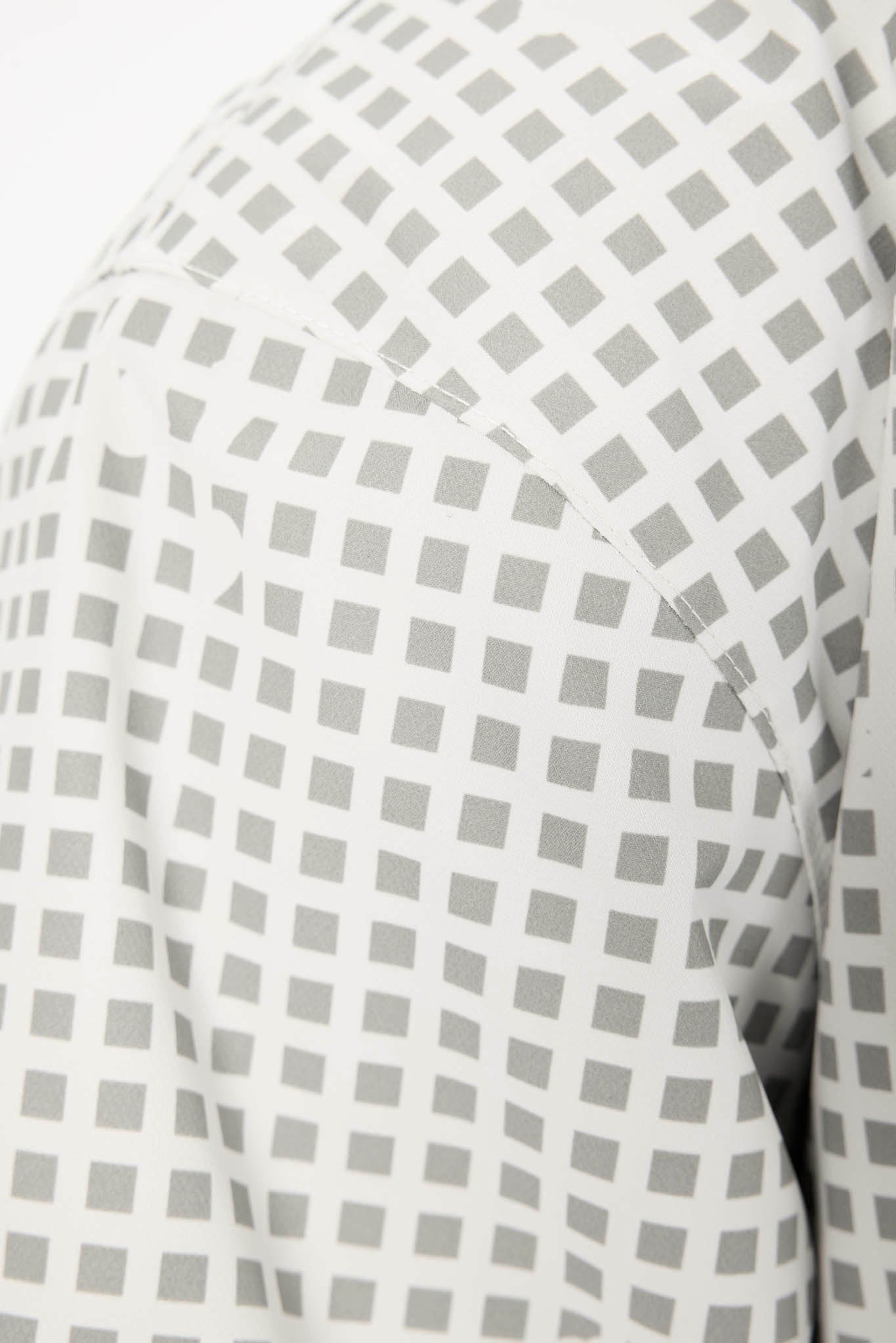 Close-up of a white fabric with a repeating gray square lattice pattern, showing the texture and stitching.