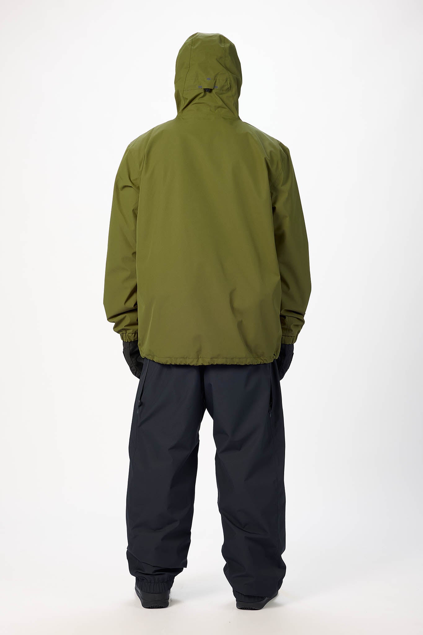 Person wearing a green raincoat and black pants on a white background