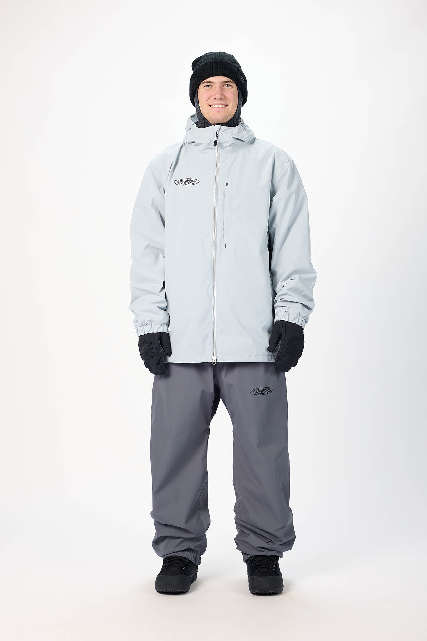Person wearing a light gray snow jacket and pants on a white background