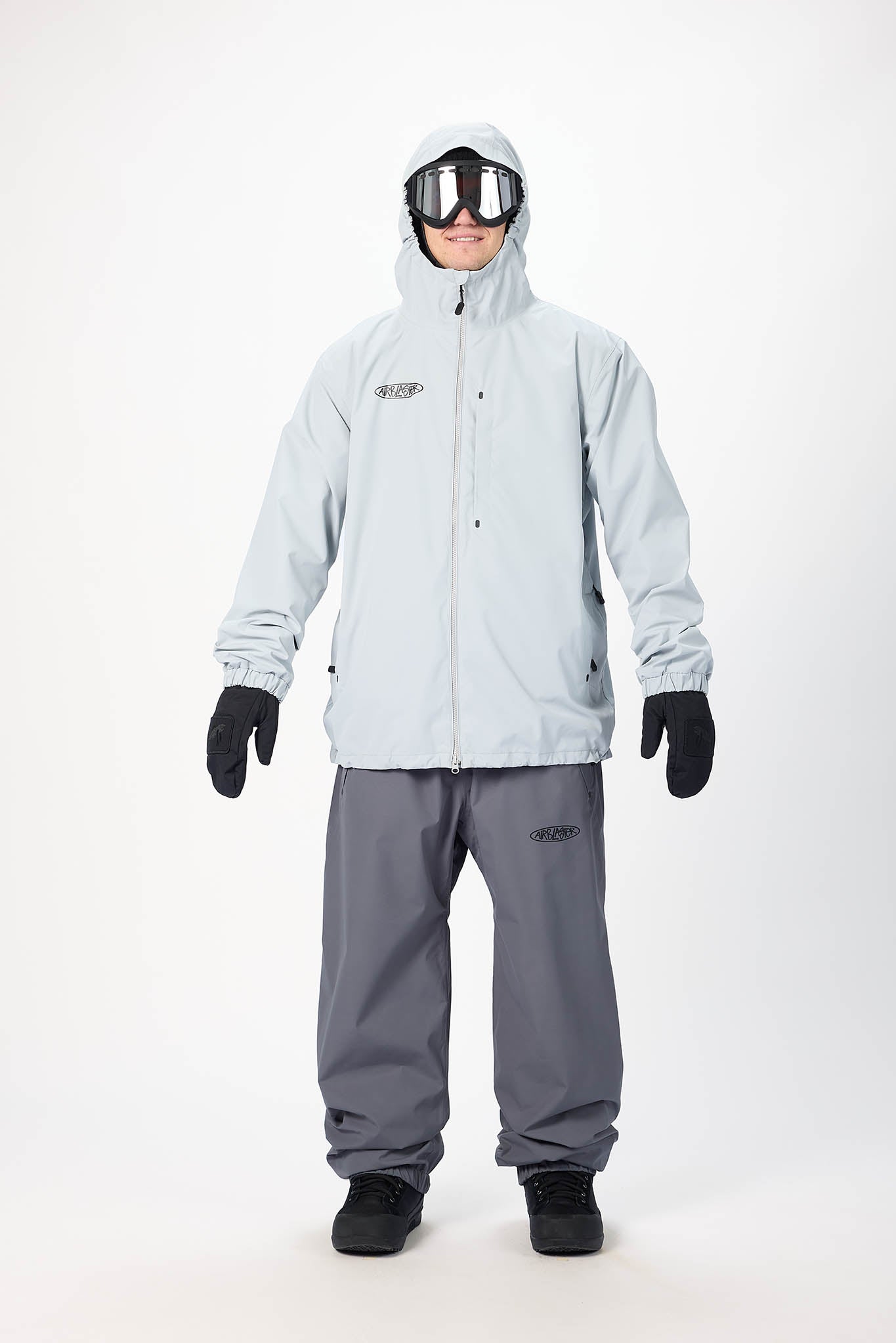 Person wearing a light gray snowsuit with goggles on a white background