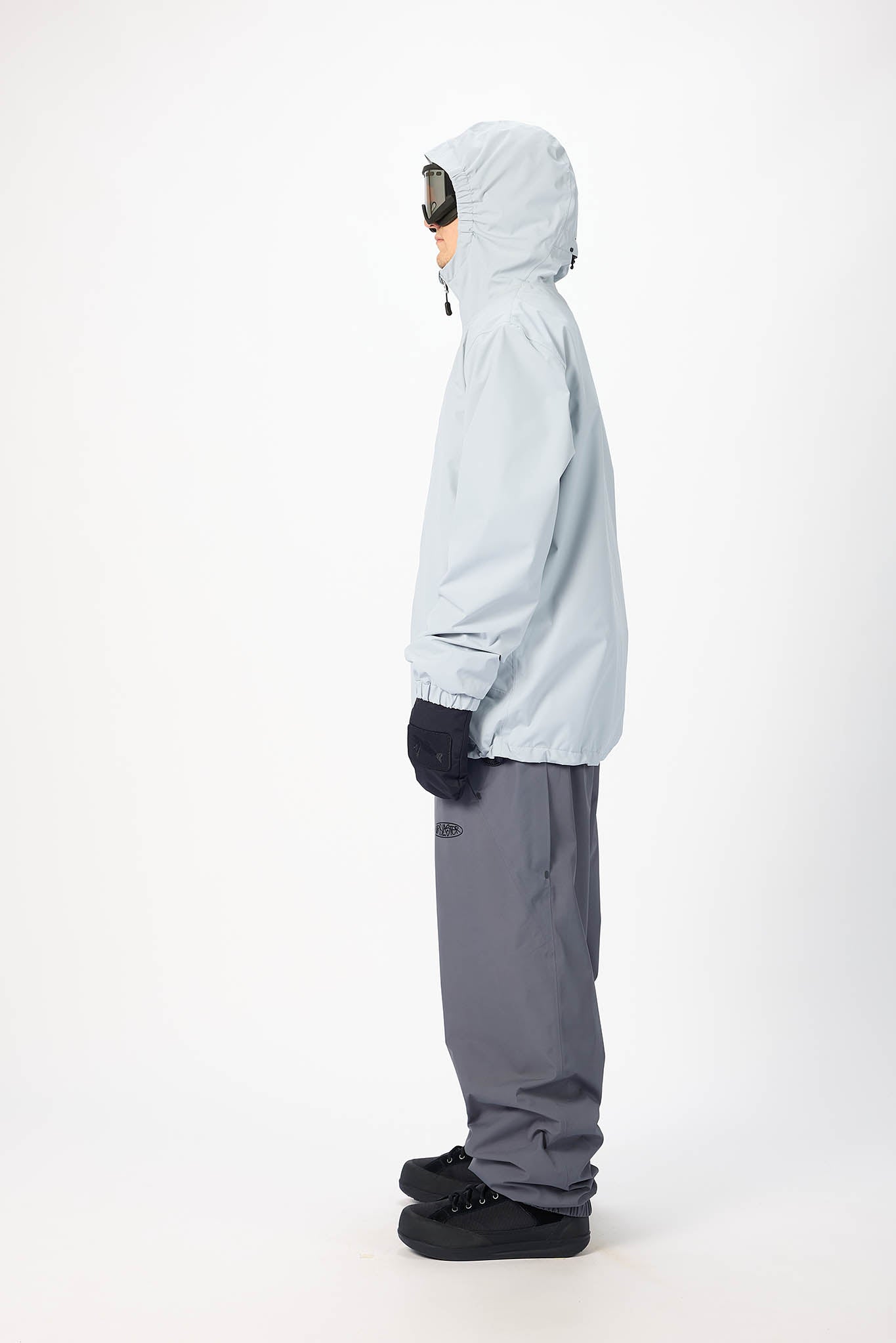 Person wearing a light blue snow jacket and gray pants on a white background
