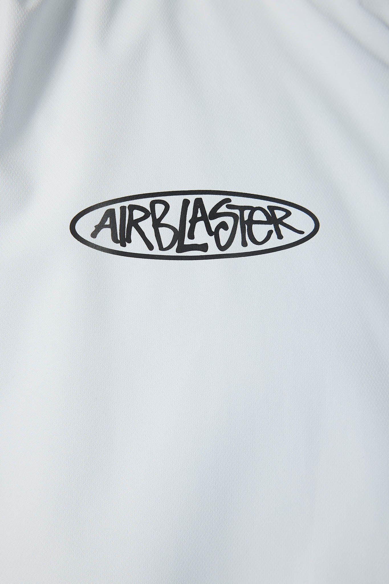 Close-up of a white shirt with 'Airblaster' logo on a light gray background