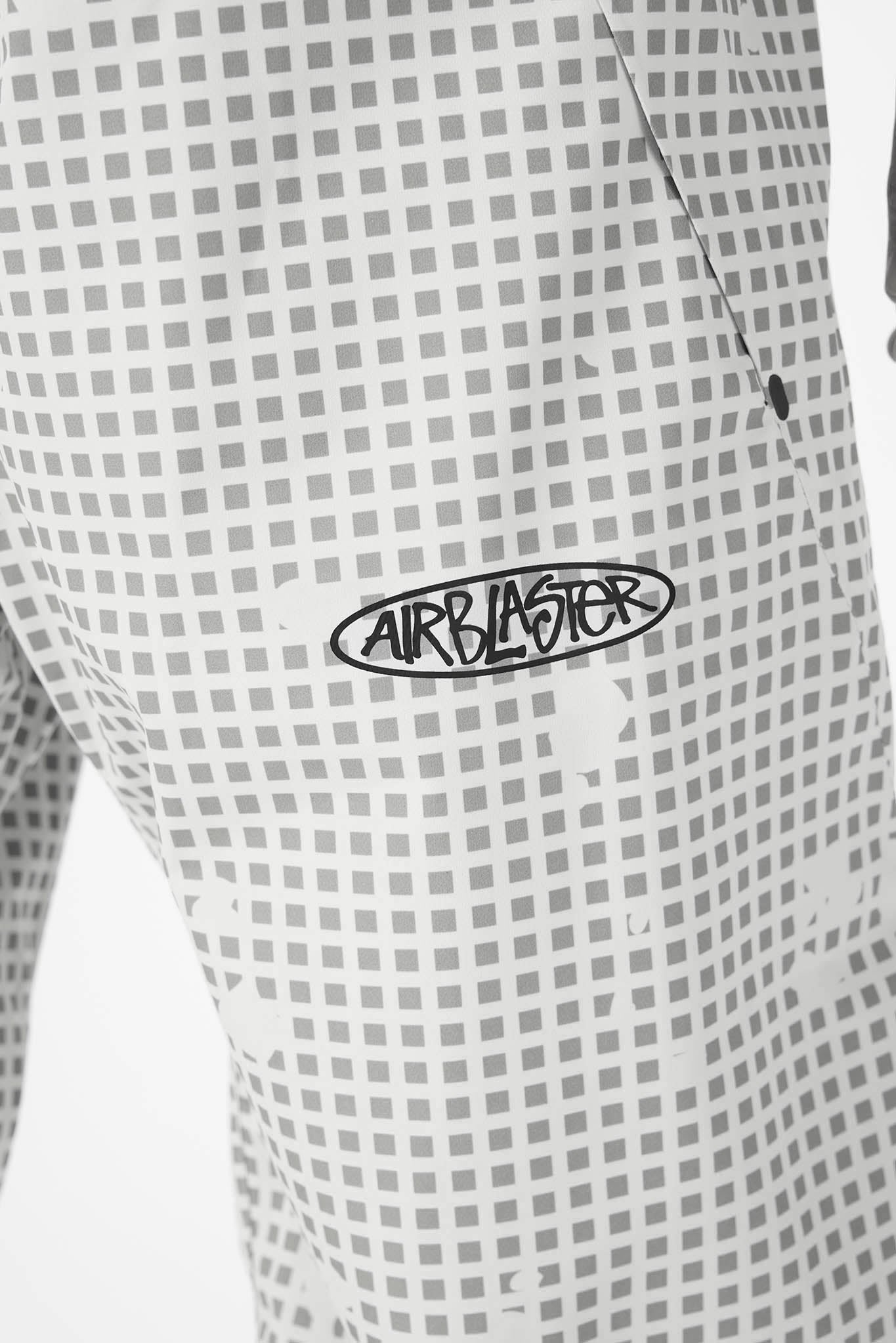 Close-up of a white and gray checkered patterned garment with a black 'AIRBLASTER' logo printed on the chest.