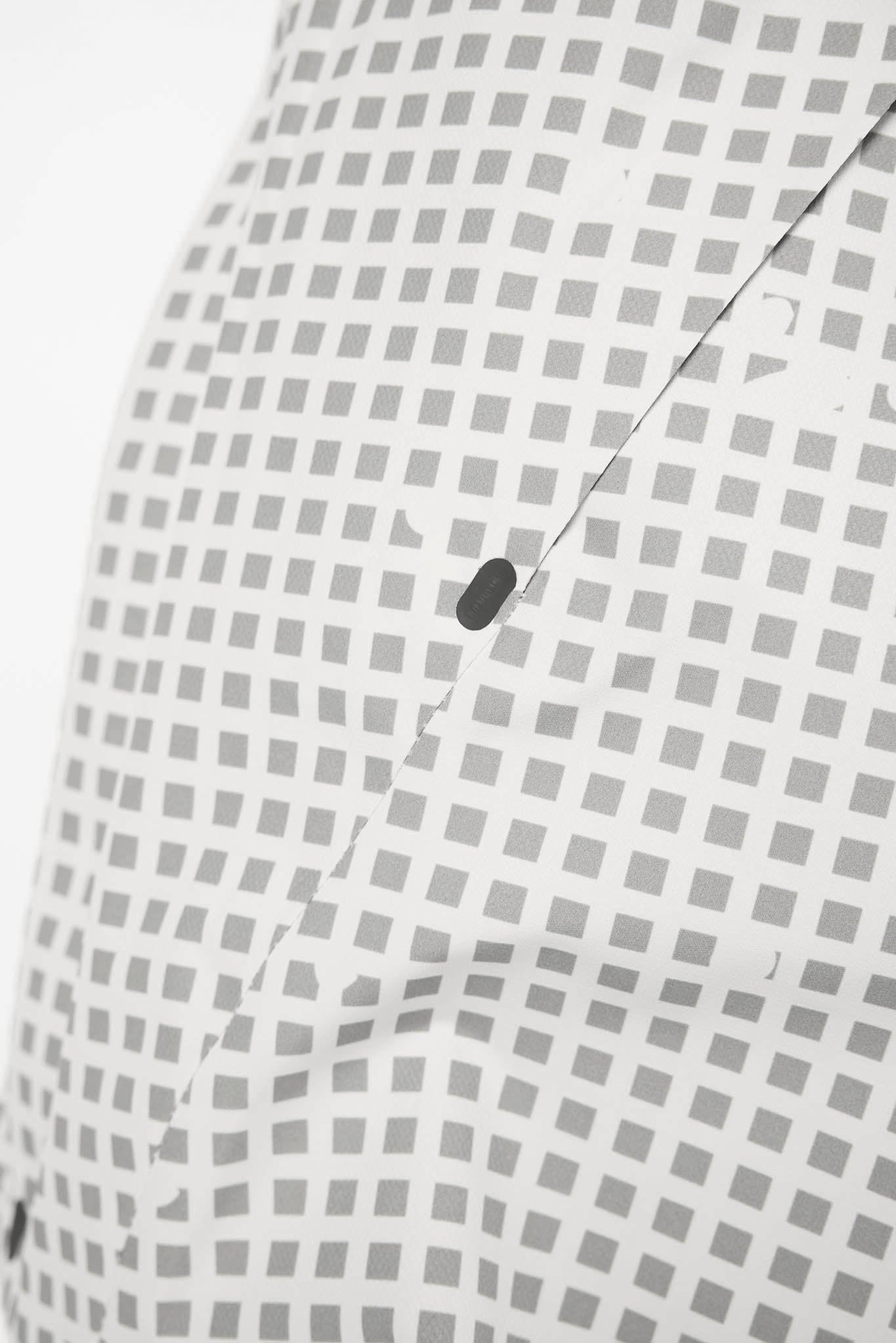 Close-up of a white garment with a repeating gray square grid pattern and a dark button detail.