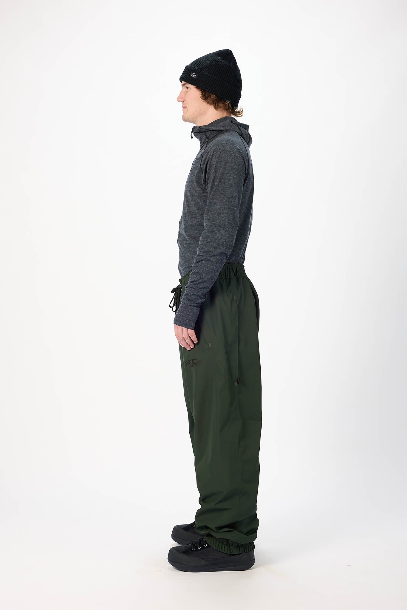 Person wearing a gray jacket and green pants on a white background