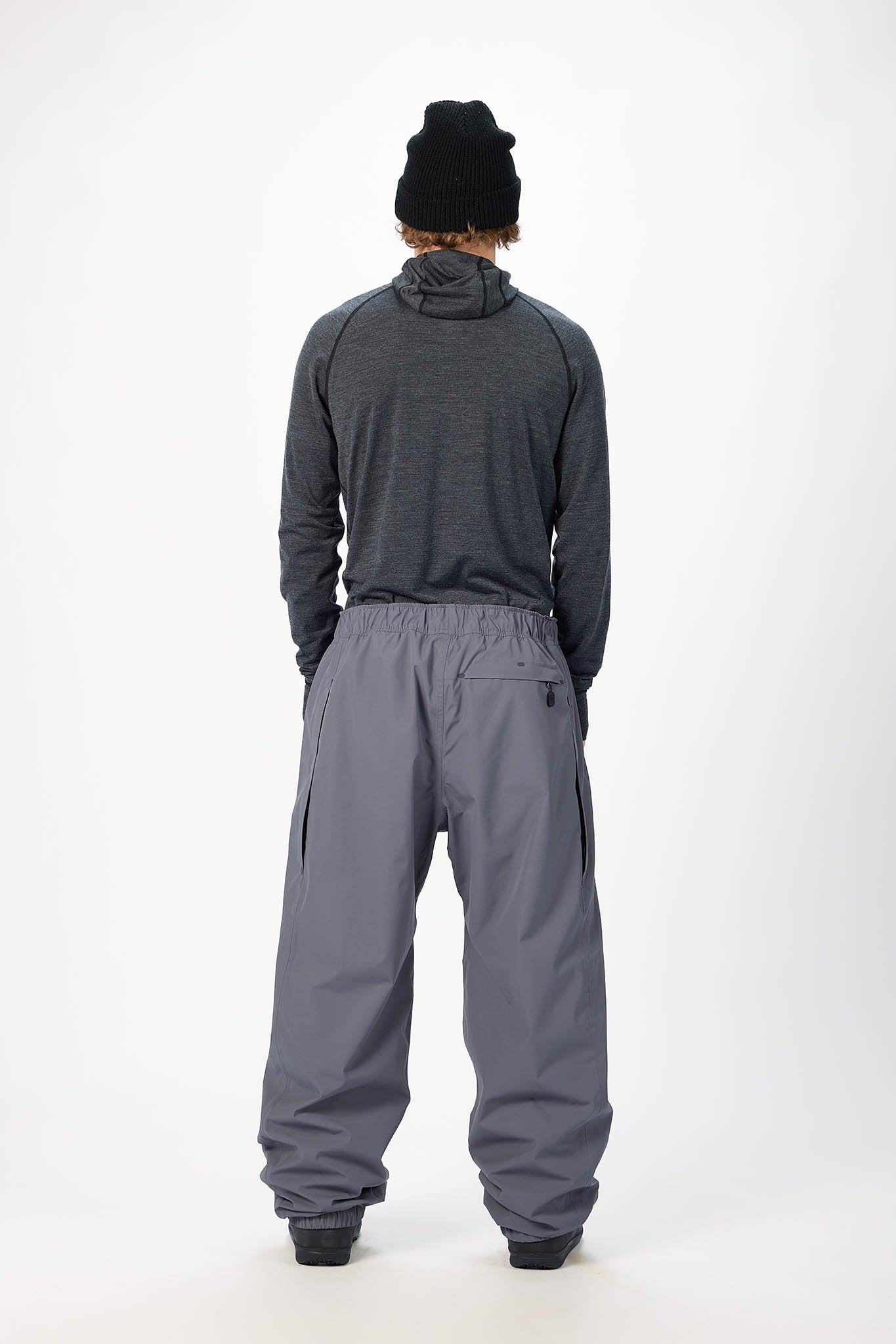 Person wearing a gray snowsuit and black beanie on a white background