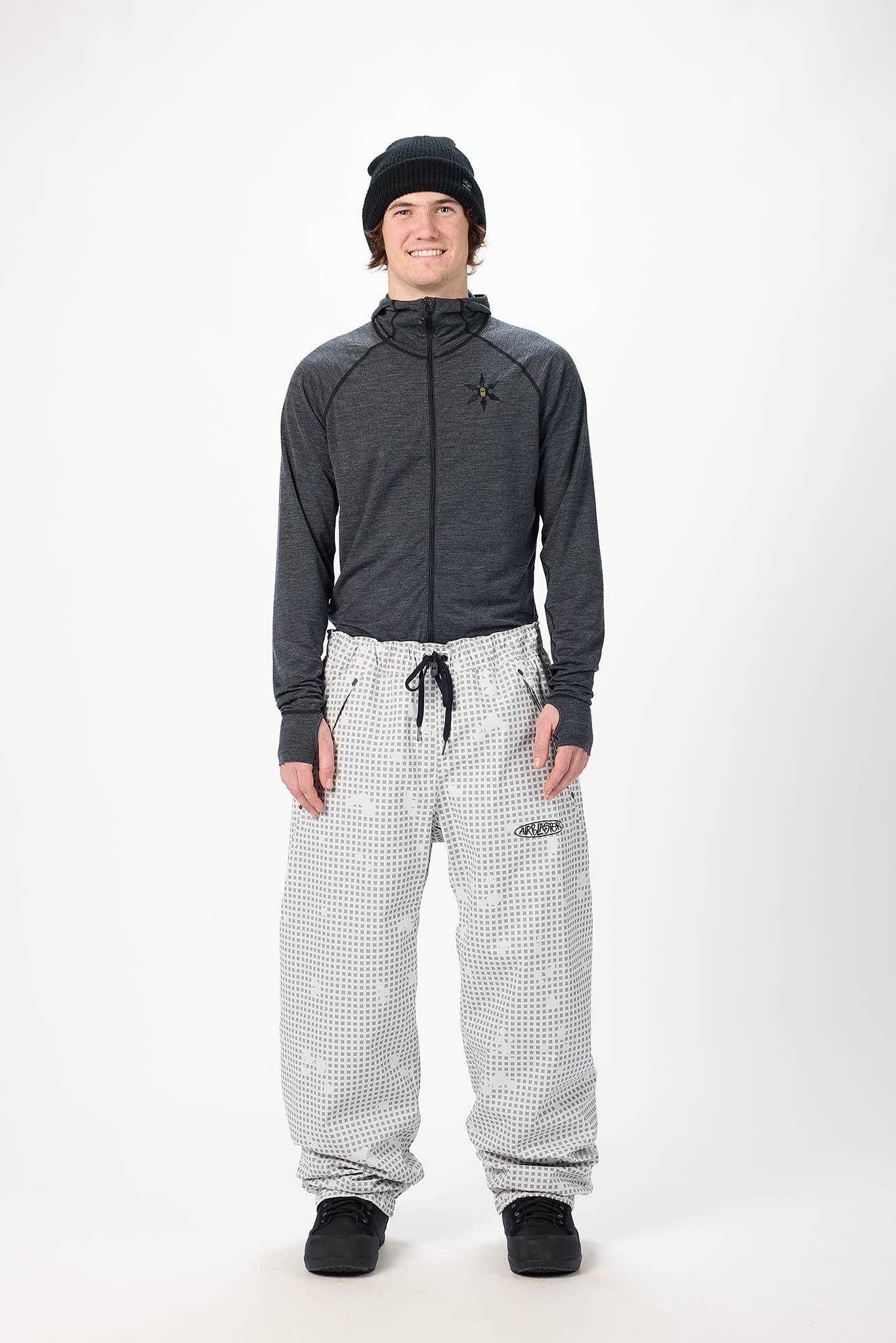 Person wearing a dark jacket and patterned pants on a white background