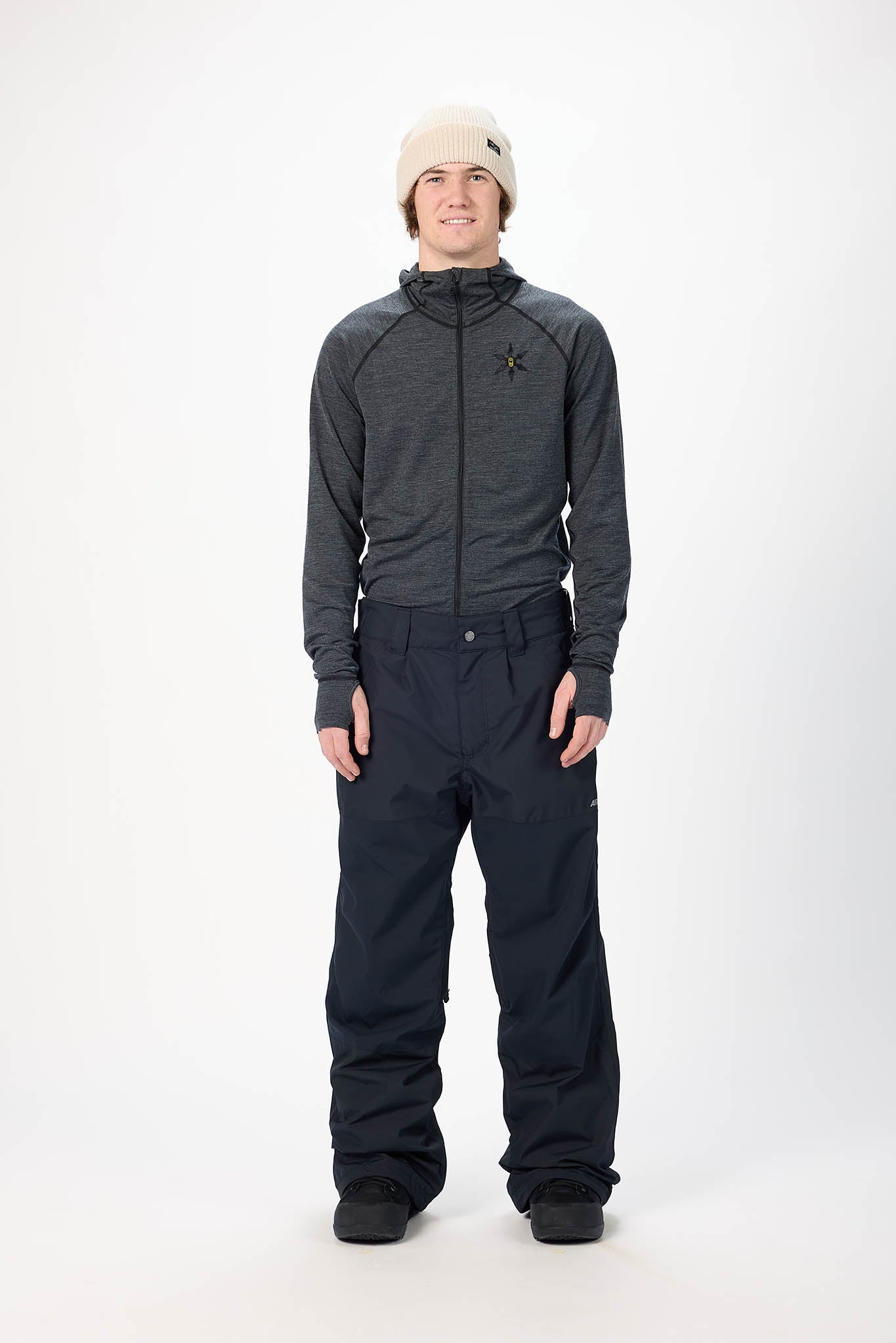 Person wearing a gray jacket and black pants on a white background