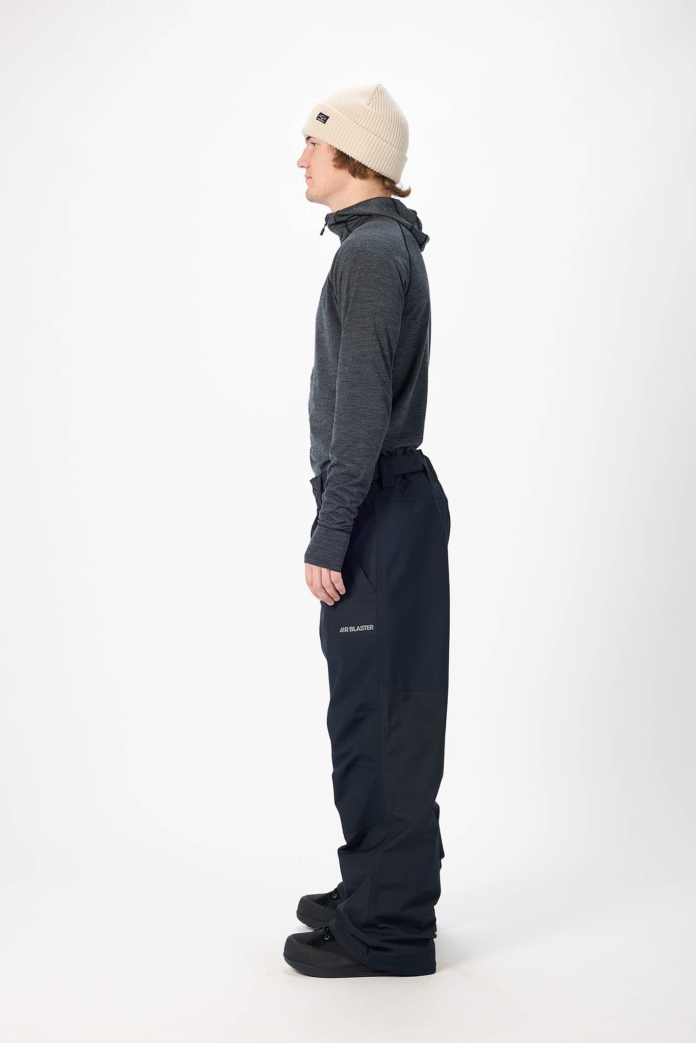 Person wearing a dark gray jacket and black pants on a white background