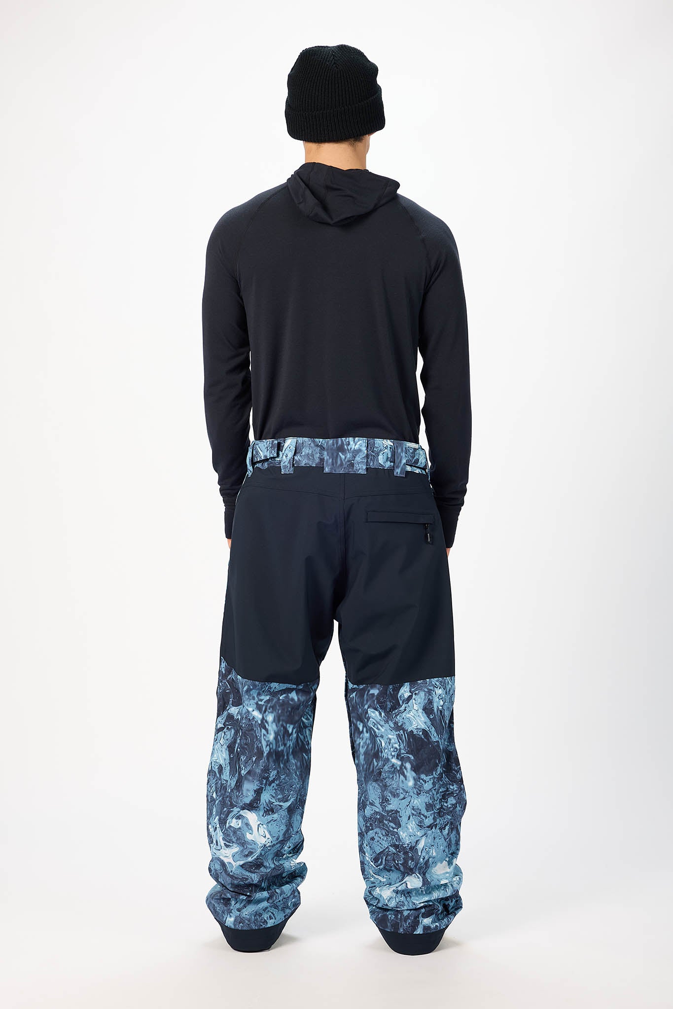 Person wearing a black hoodie and blue camouflage pants on a white background