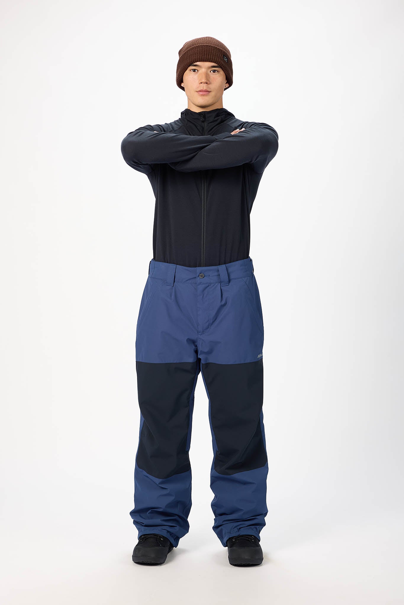 Person wearing a black top and blue pants with a white background