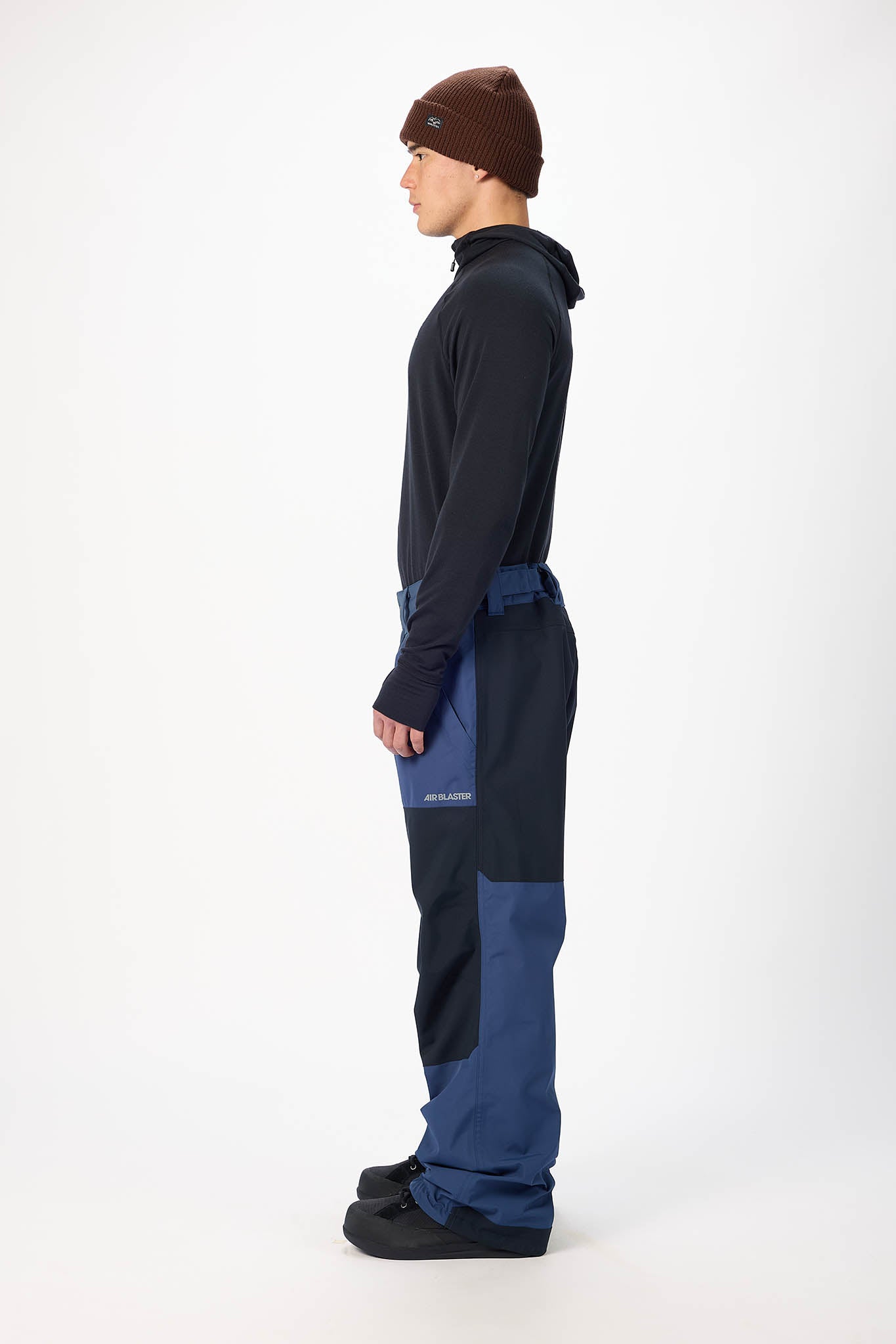 Person wearing a dark blue snowmobile suit with a brown beanie on a white background