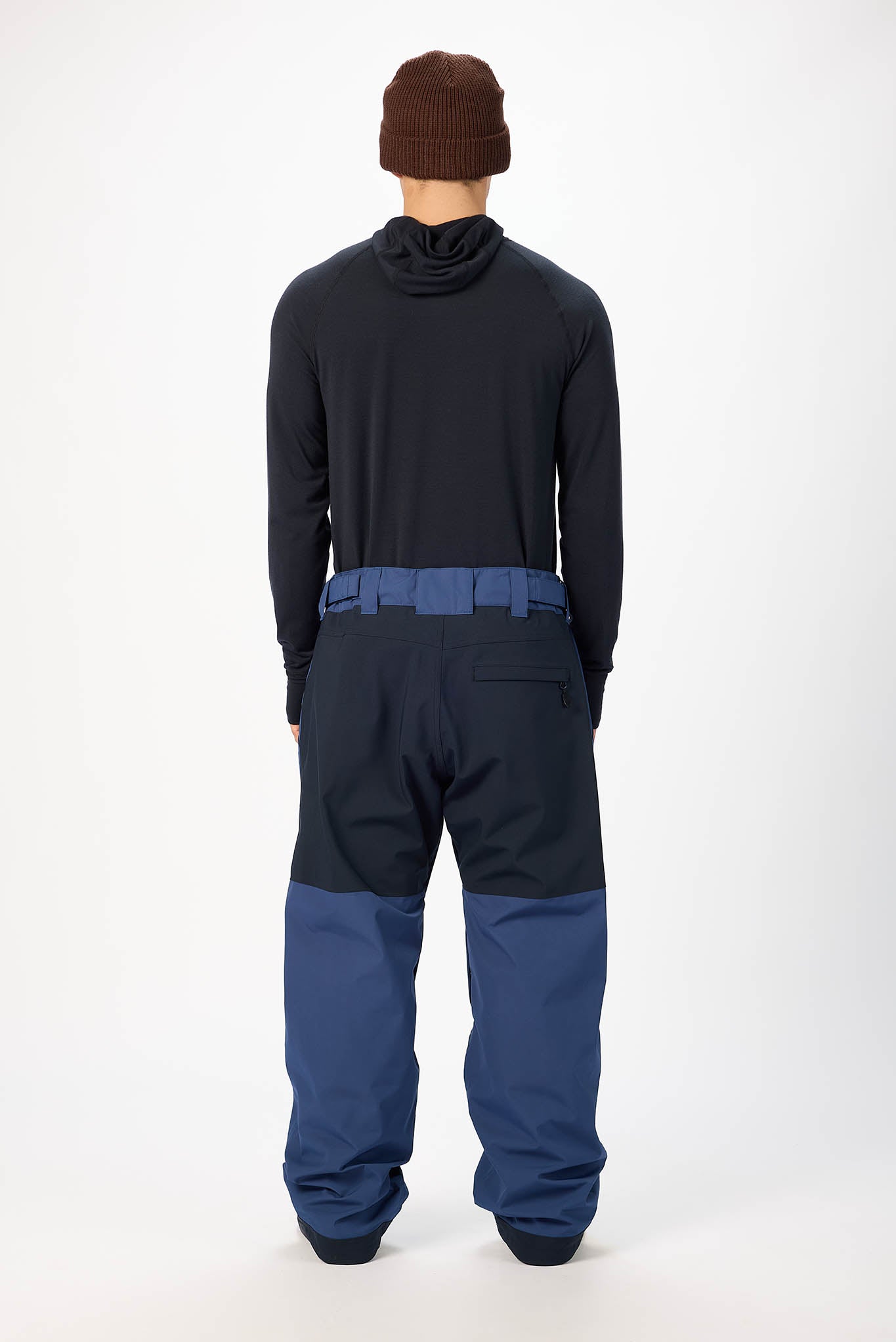 Person wearing a black jacket and blue pants with a brown beanie on a white background
