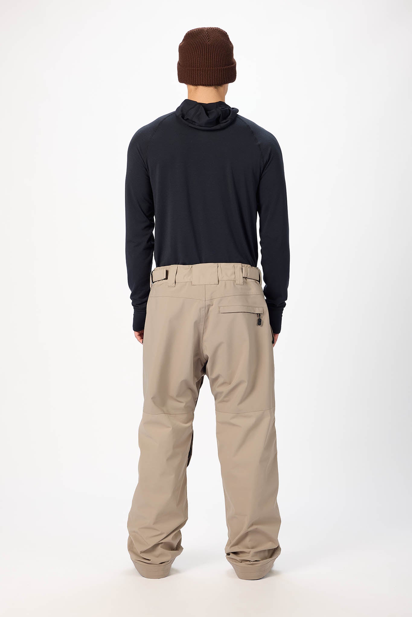 Person wearing a dark long-sleeve shirt and beige pants on a white background