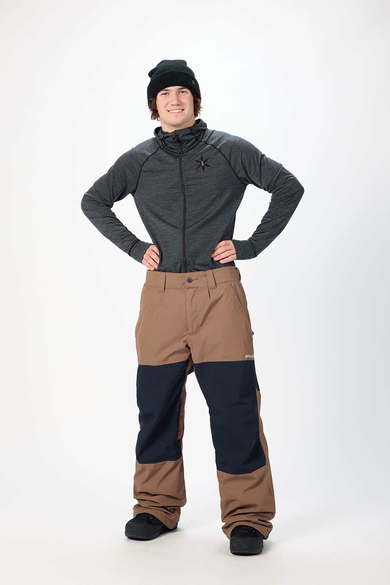 Person wearing a gray jacket and brown pants on a white background