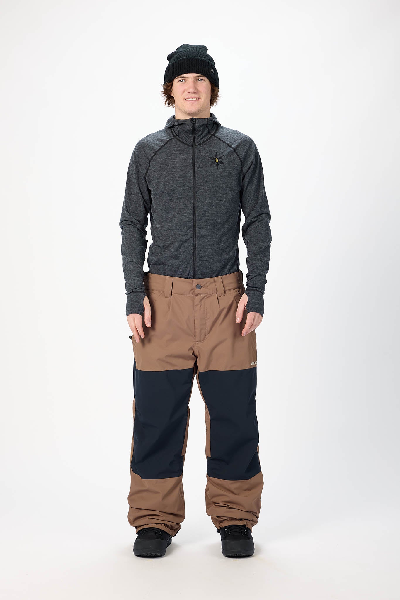 Person wearing a gray jacket and brown pants on a white background