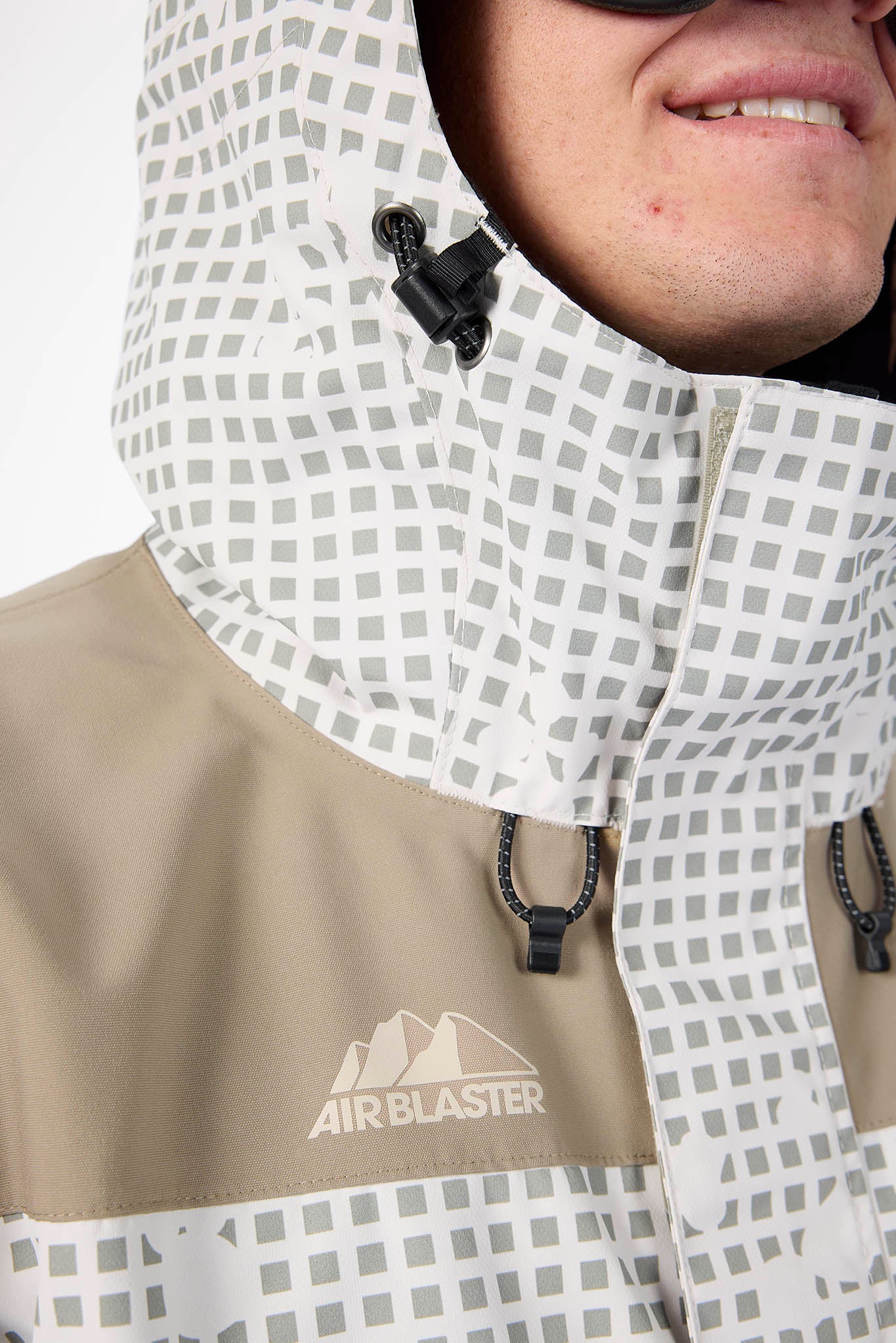 Person wearing a beige jacket with a patterned hood, featuring the Air Blaster logo.
