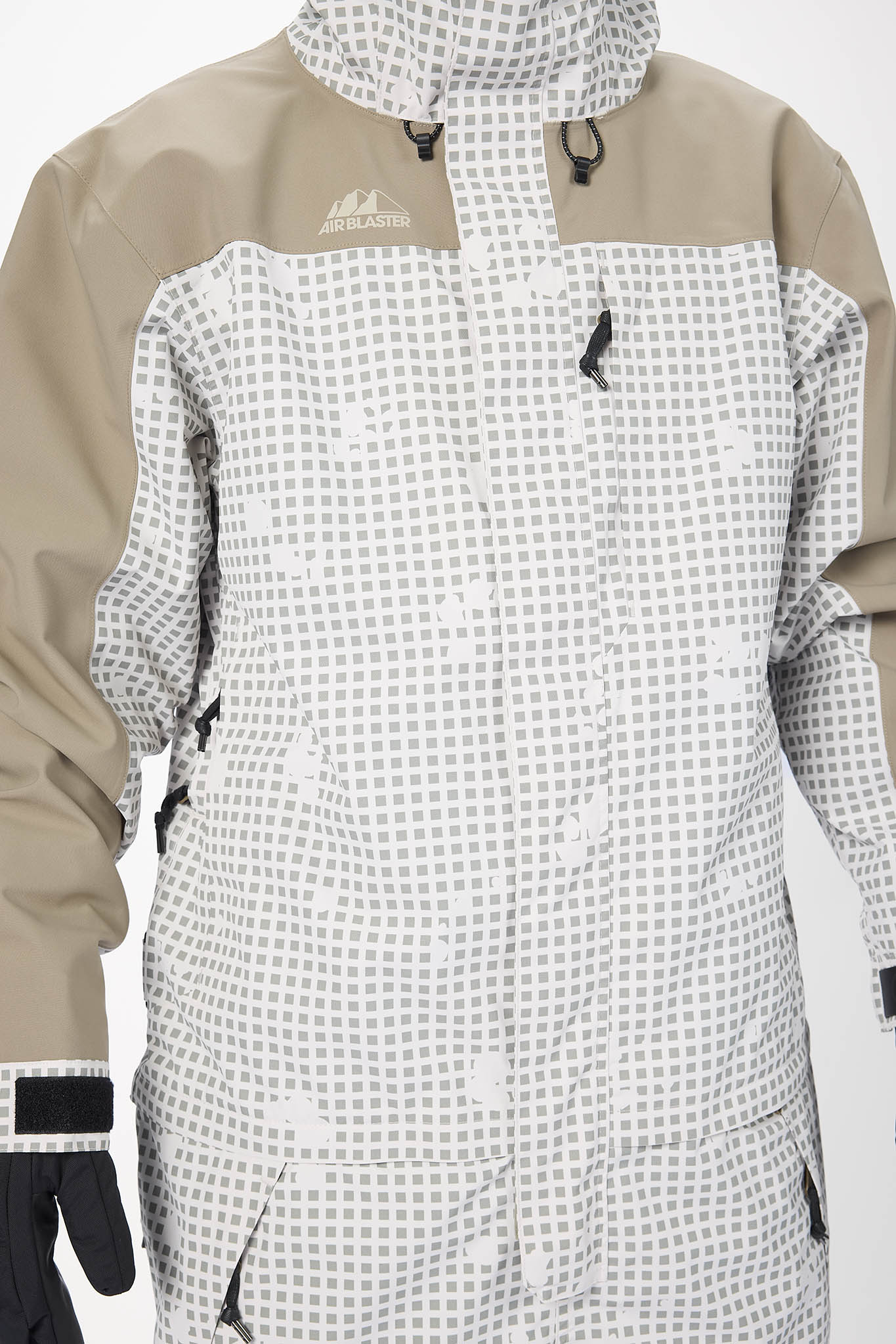 Close-up of a person wearing a beige and white checkered jacket with a hood on a light gray background.