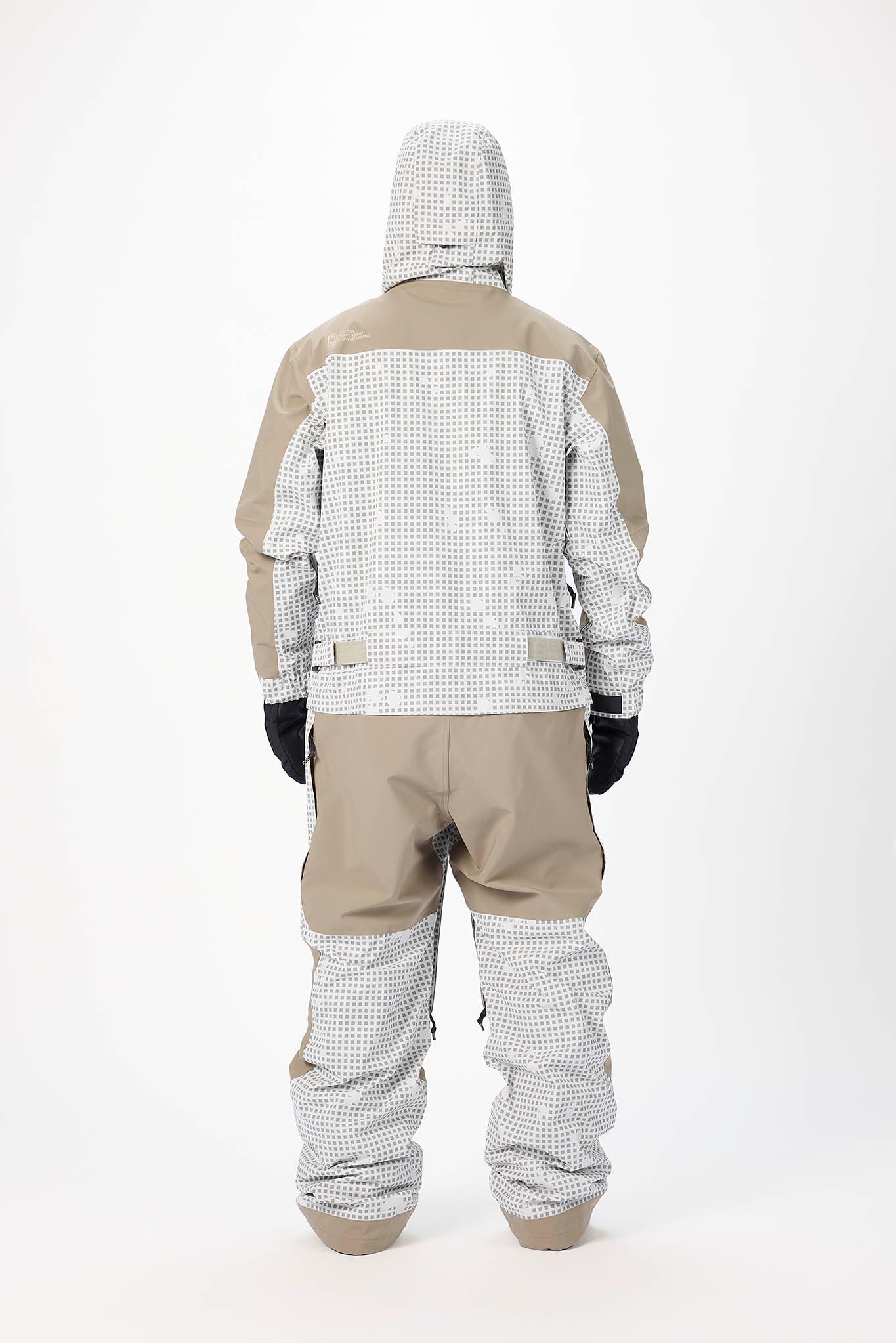 Person wearing a beige and white checkered snowsuit on a white background