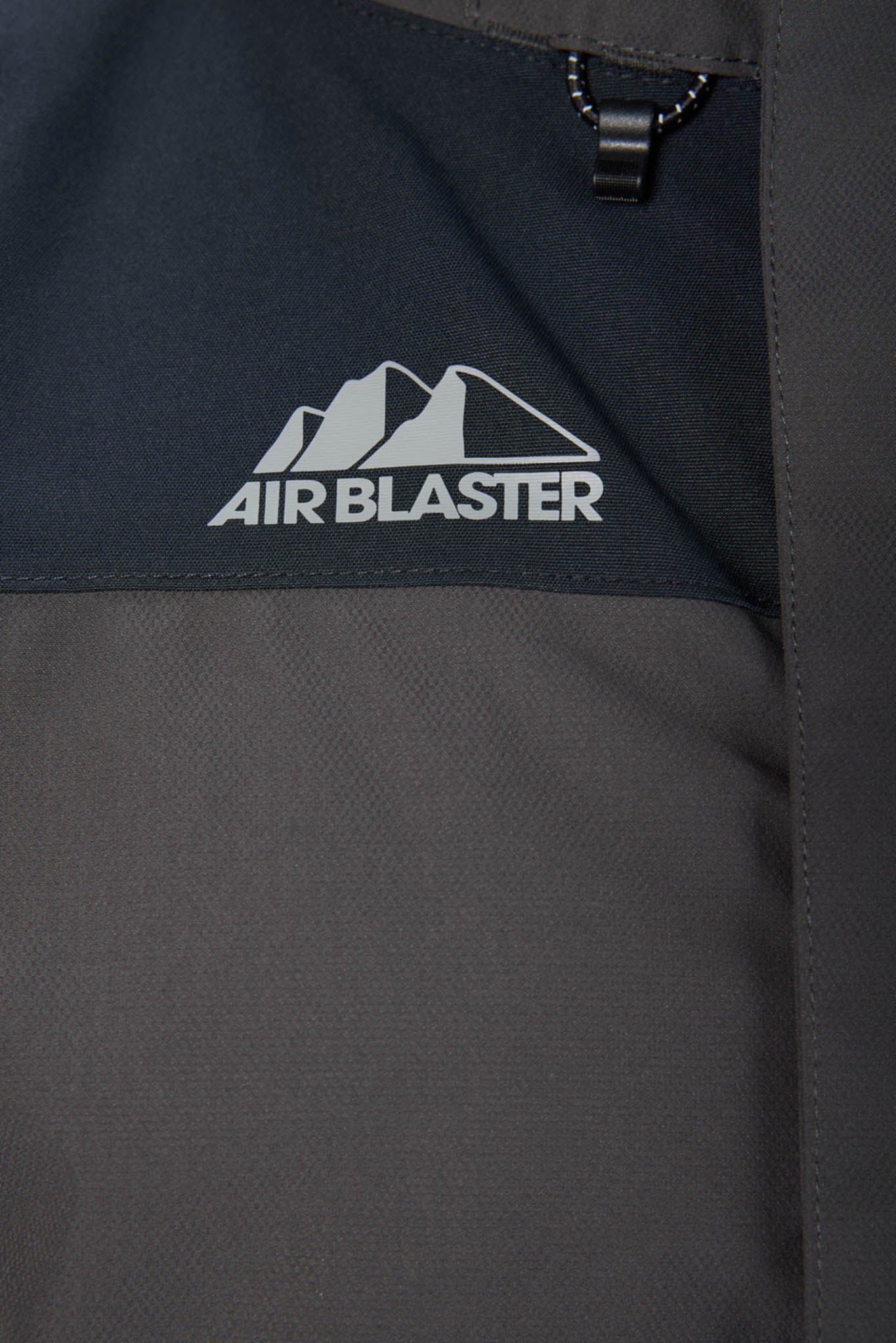 Close-up of a black jacket with 'Air Blaster' logo on a dark background