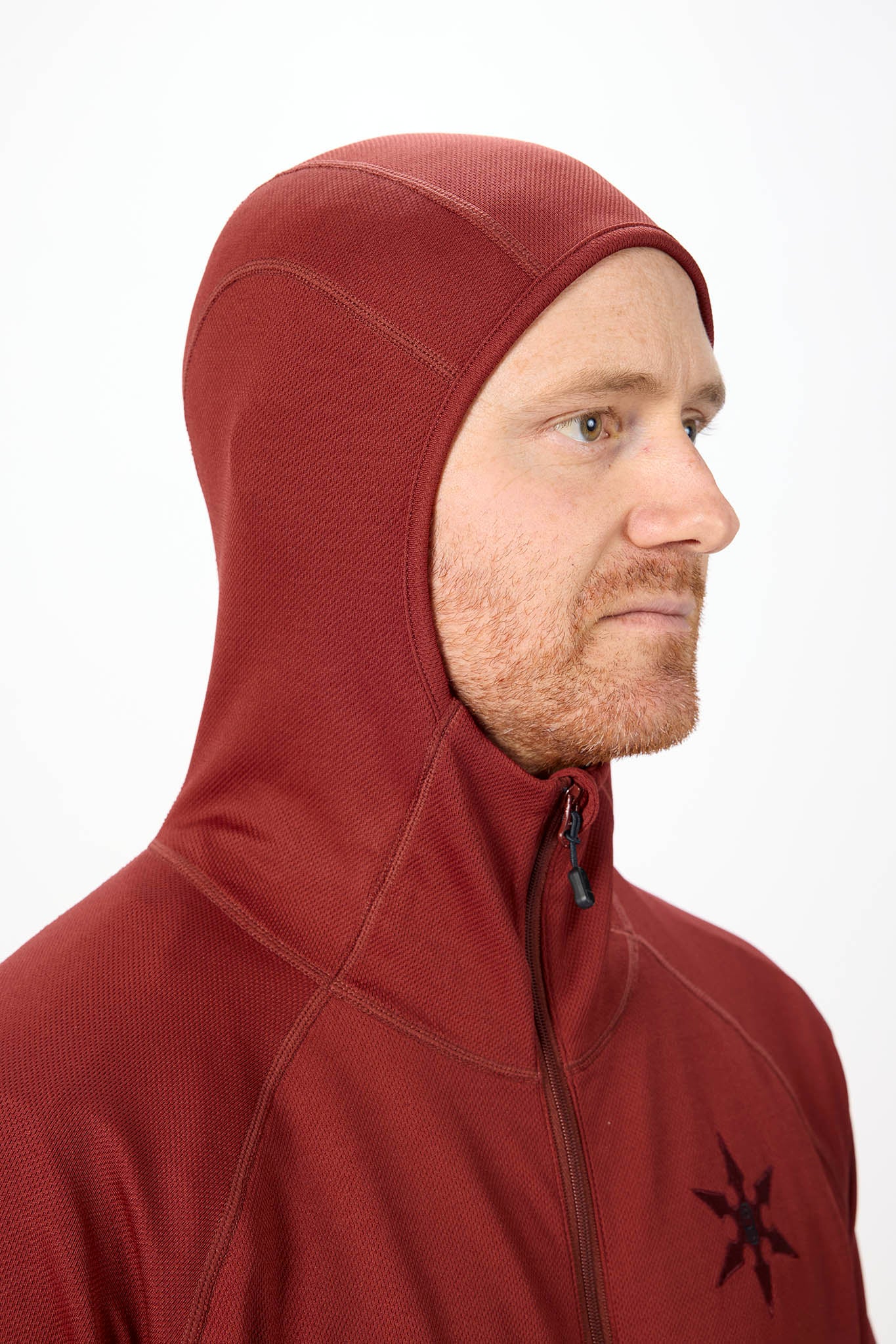 Close up of a model wearing a hooded onesie in a red color with white background