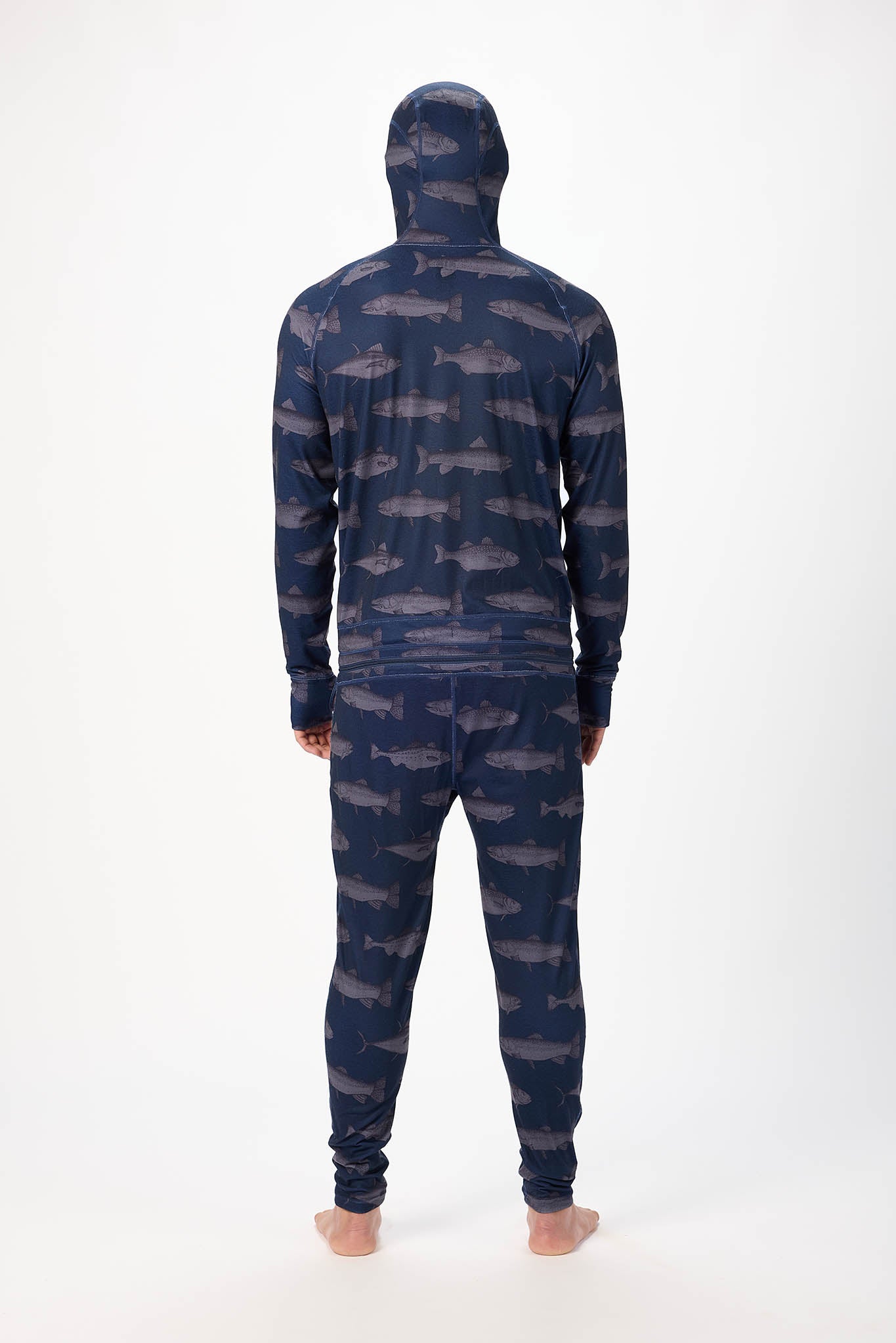 viewed from behind A man wearing a fish patterned onesie with a hooded with a zipper and jogger pants, standing against a plain white studio background.