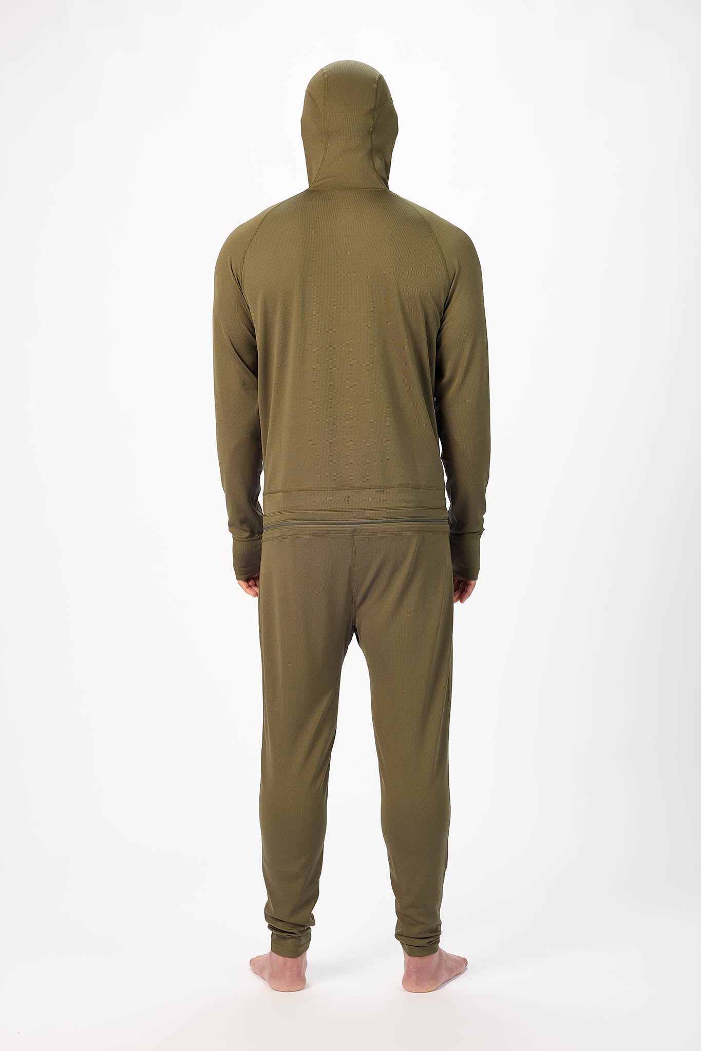 viewed from behind A man wearing a Olive  onesie with a hooded with a zipper and jogger pants, standing against a plain white studio background.