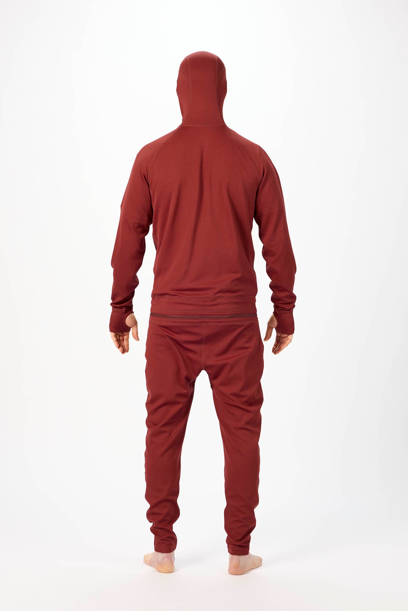 viewed from behind A man wearing a matching burgundy onesie with a hooded zip-up jacket and jogger pants, standing against a plain white studio background.