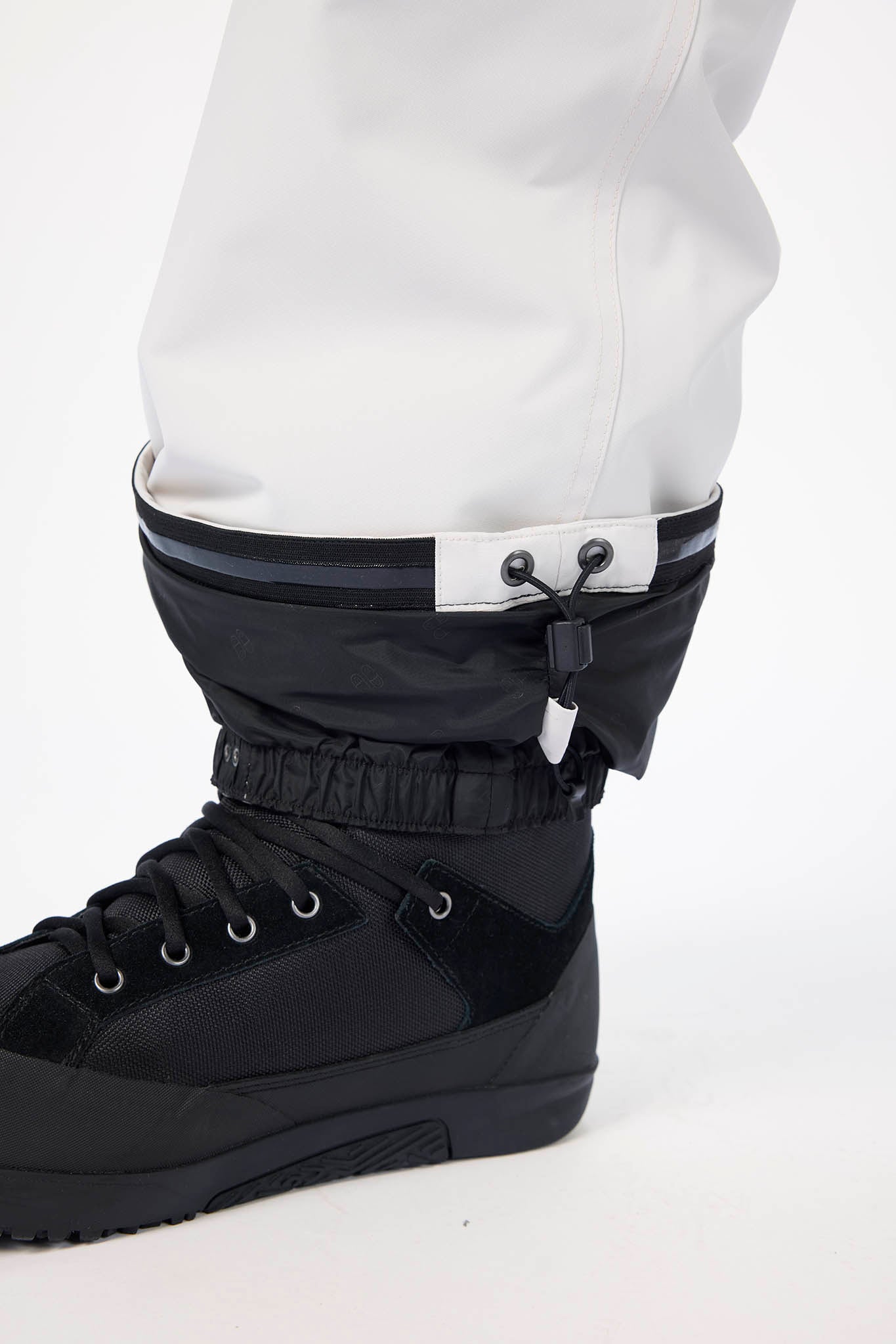 Black snow boot with white pants on a white background