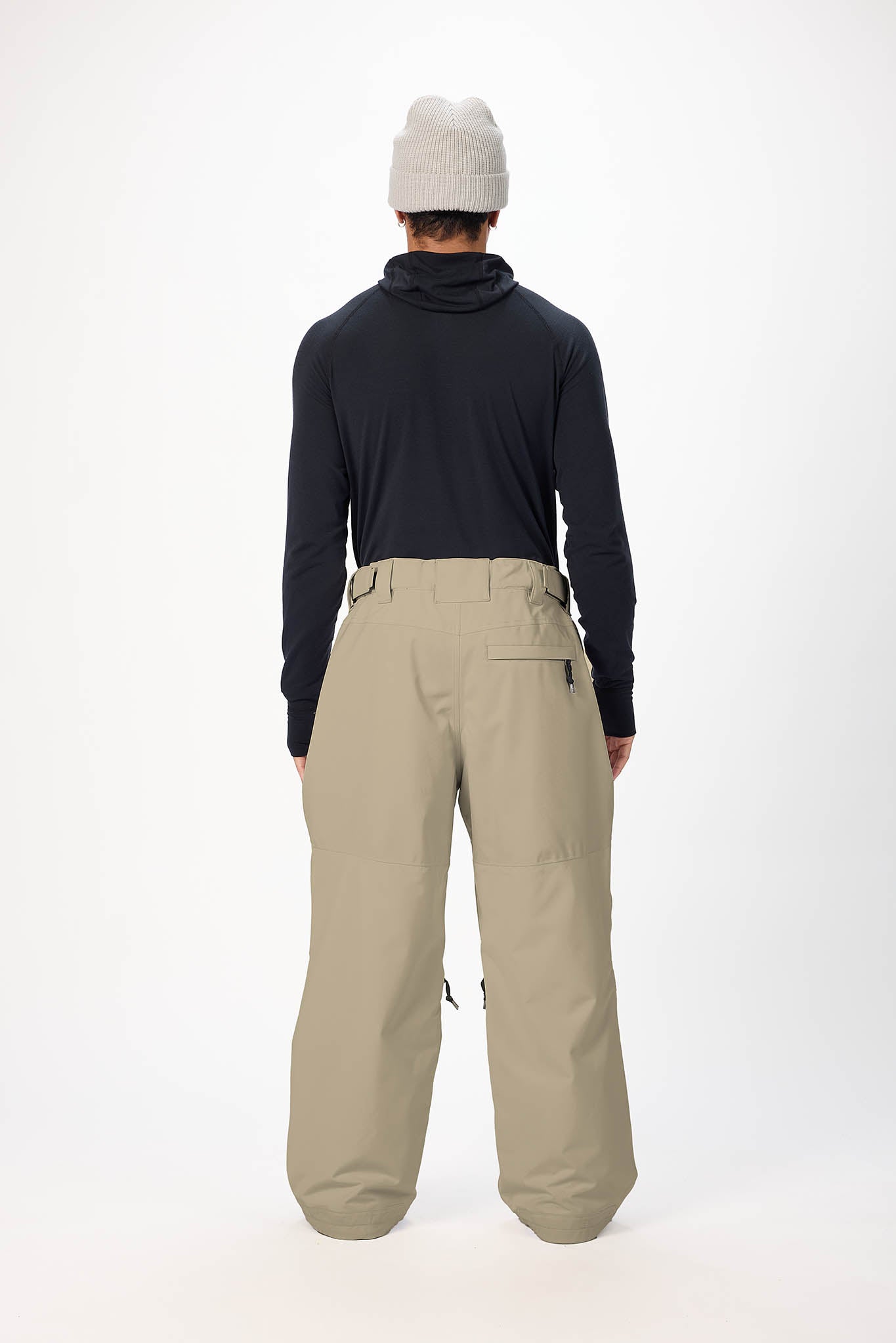 Person wearing a black jacket and beige pants on a white background