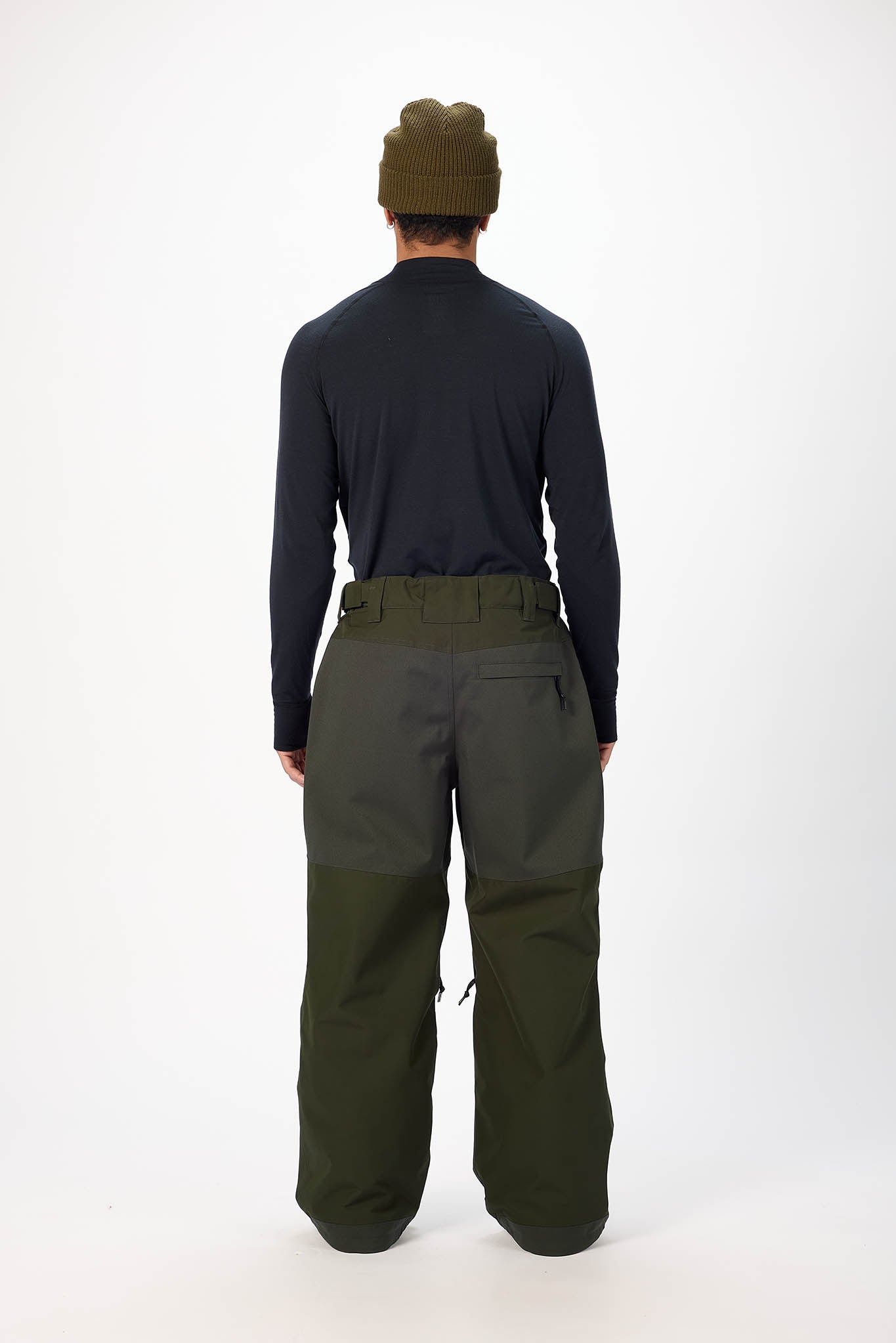 Person wearing a black long-sleeve shirt and green pants on a white background