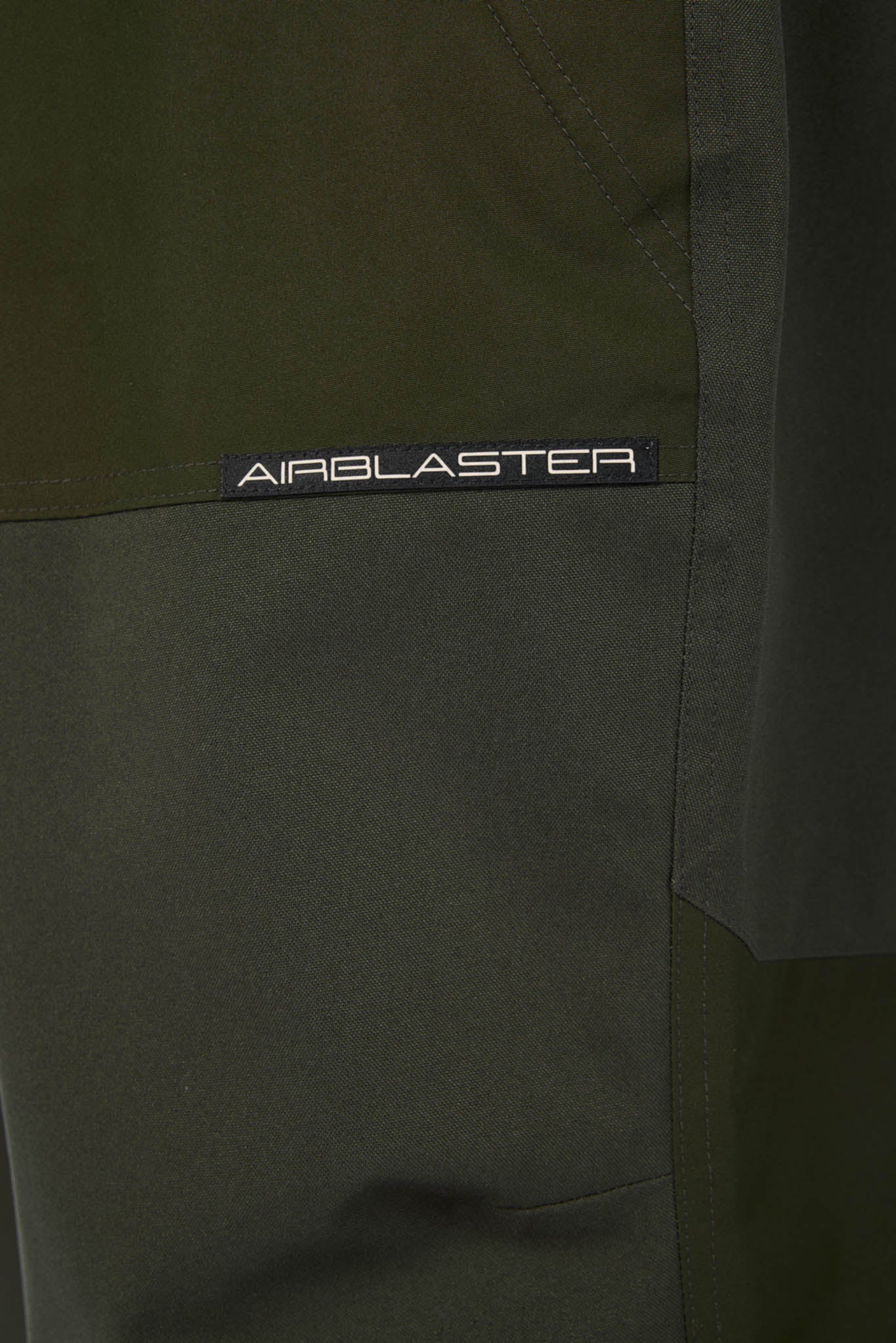 Close-up of a green jacket with 'Airblaster' branding on a dark background
