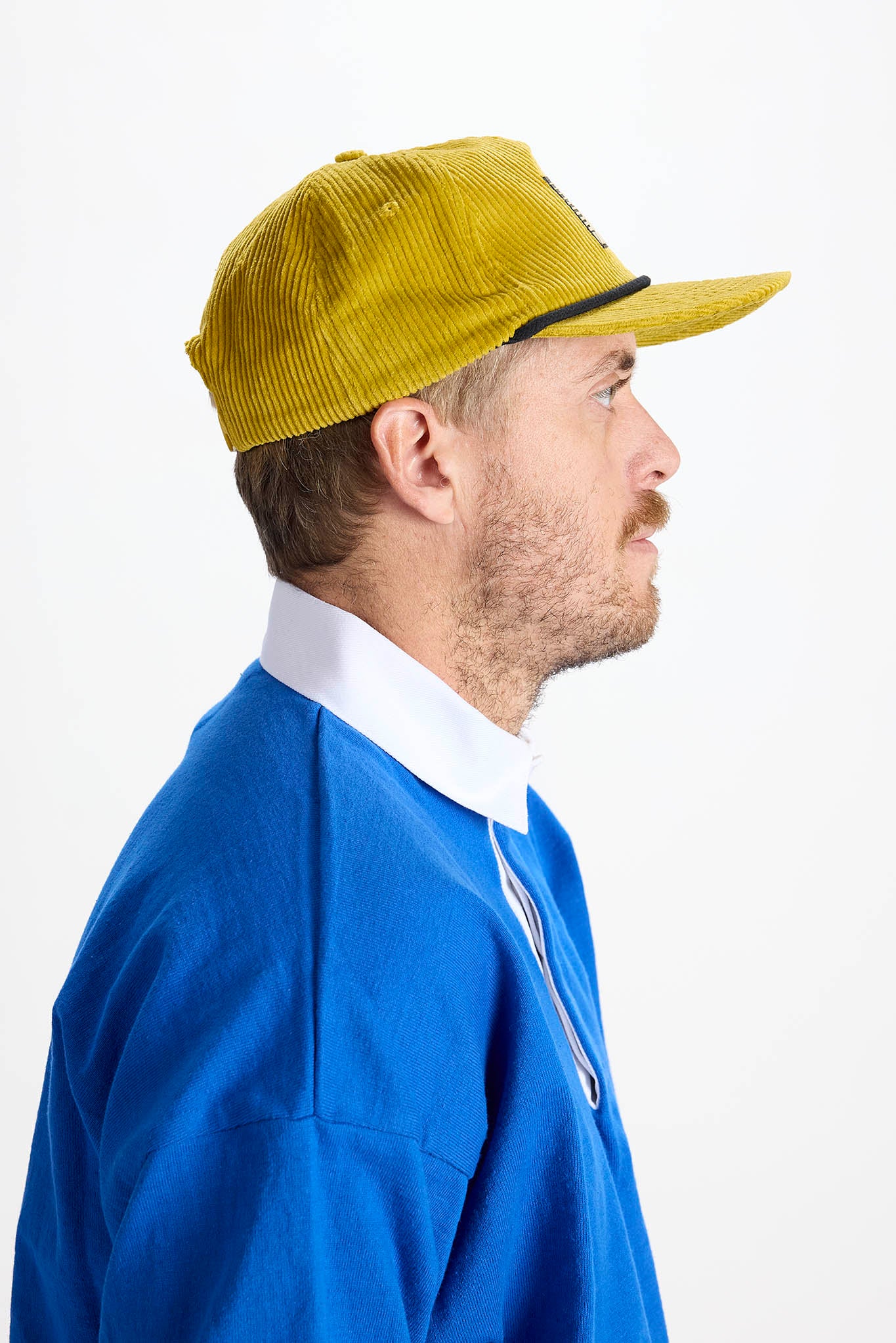 side profile of model wearing yellow baseball cap