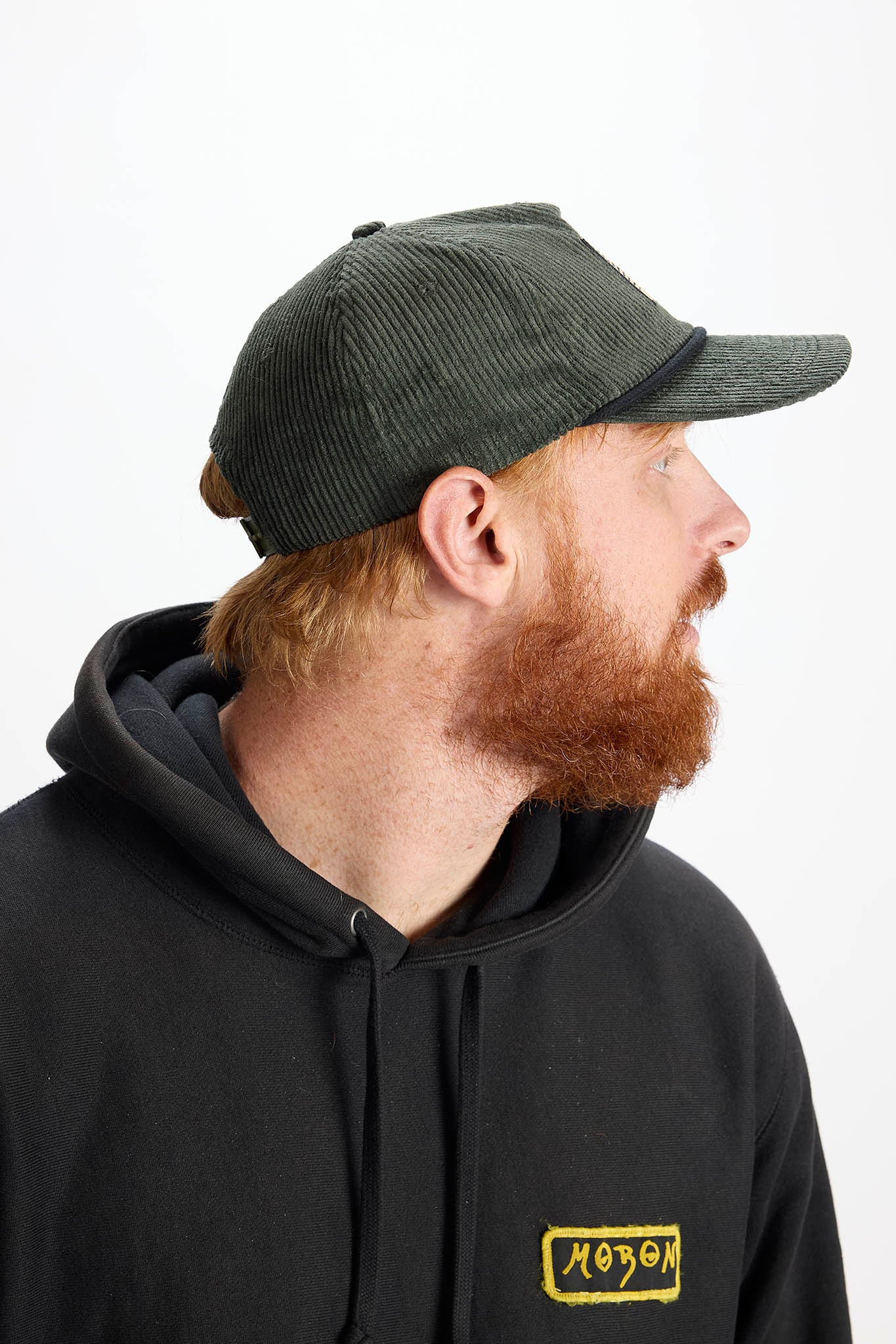 side profile model wearing a green baseball cap with white background