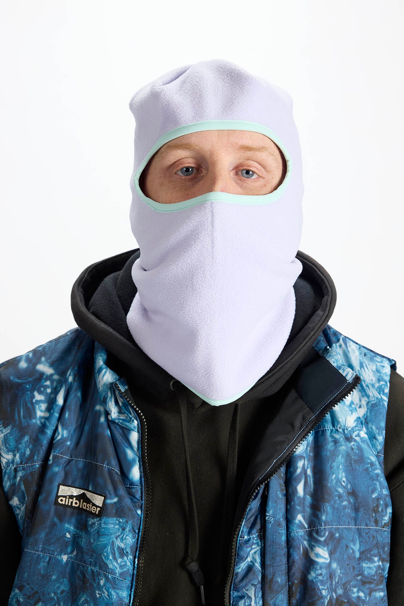 A man wearing a light purple balaclava mask with a brown leopard print pattern, paired with an olive green hoodie against a plain white background.