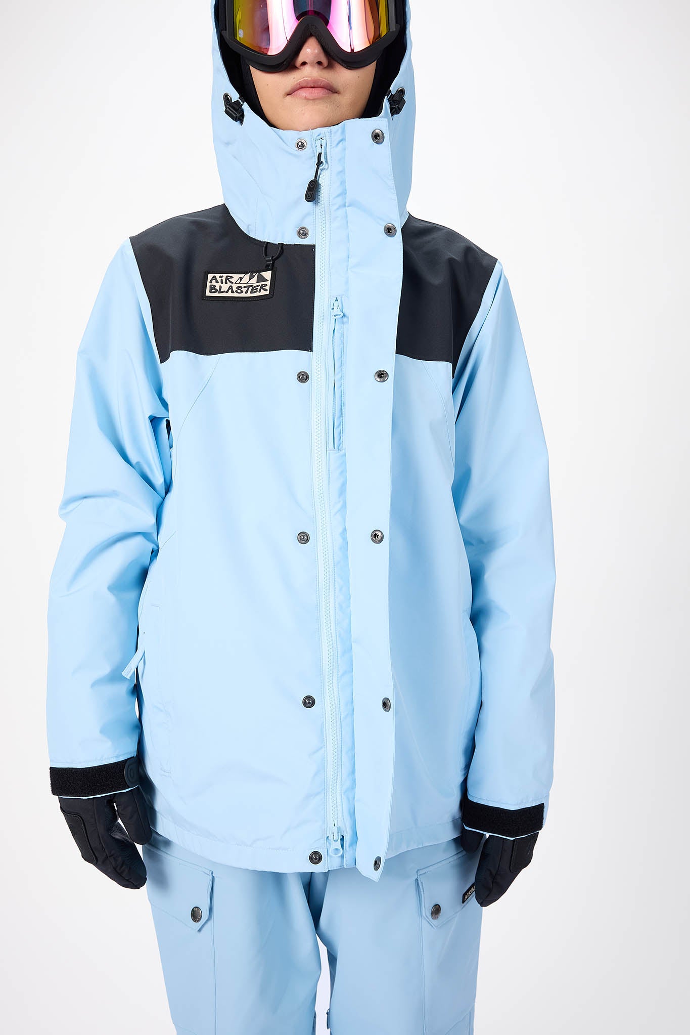 Person wearing a light blue snowsuit with black accents on a white background
