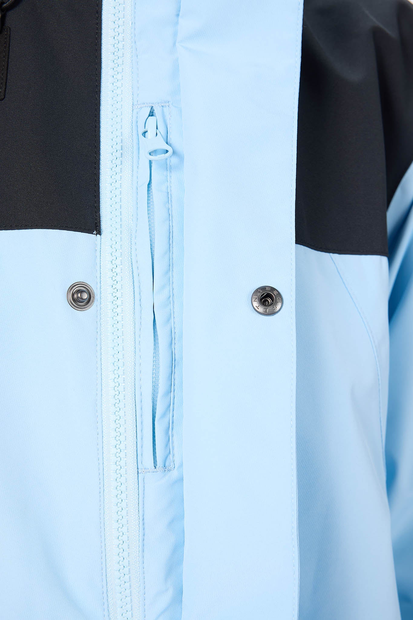 Close-up of a light blue jacket with black accents and zippers.