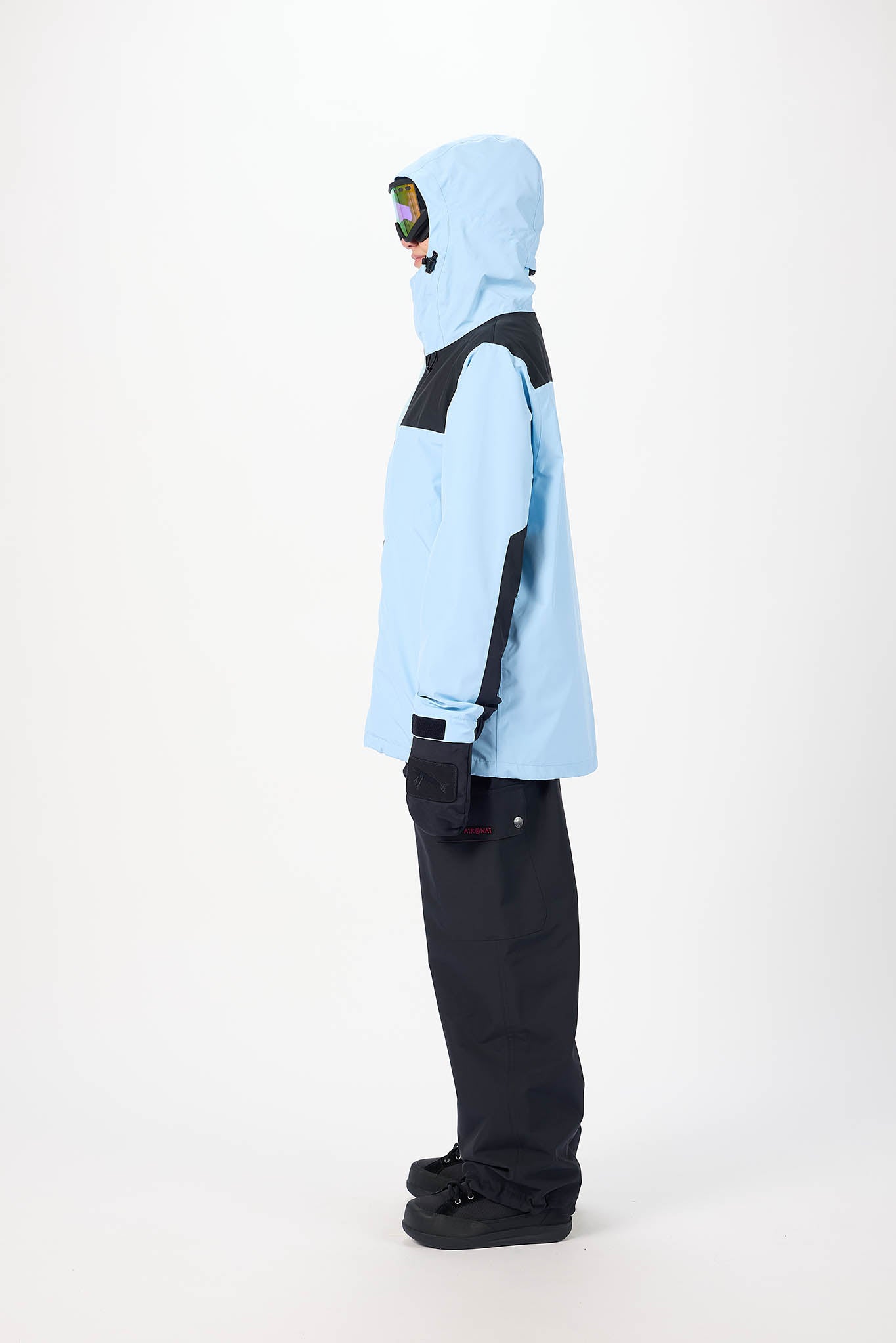 Person wearing a light blue snow jacket with black accents on a white background