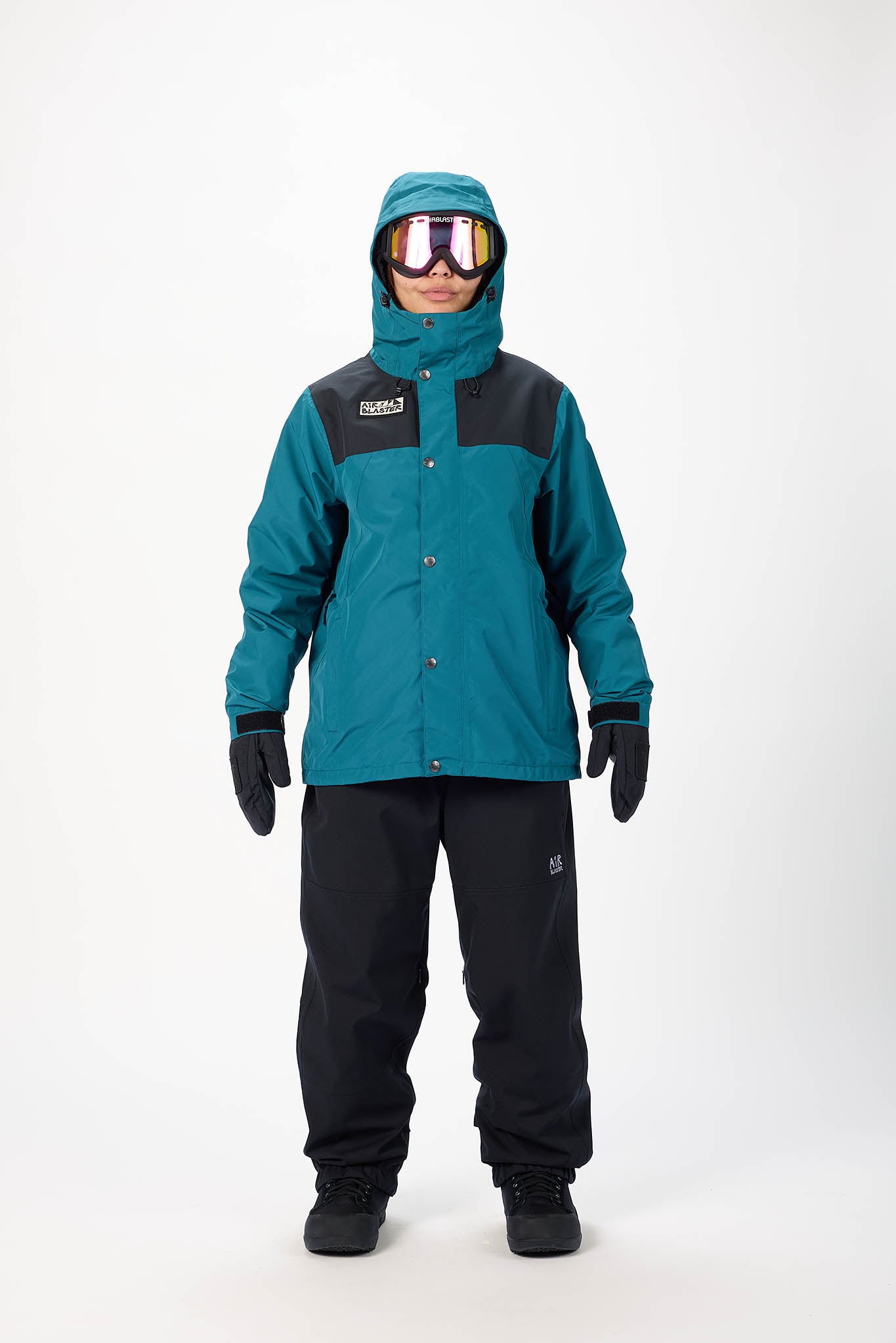 Person wearing a teal and black snowsuit with goggles on a white background