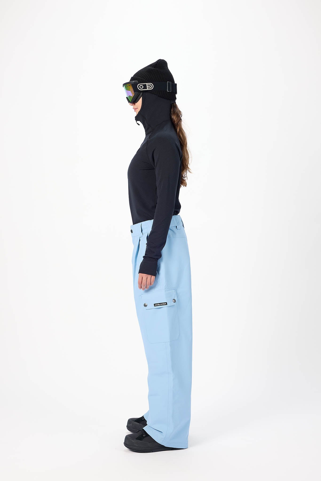 Person wearing a black jacket, light blue pants, and black ski boots on a white background