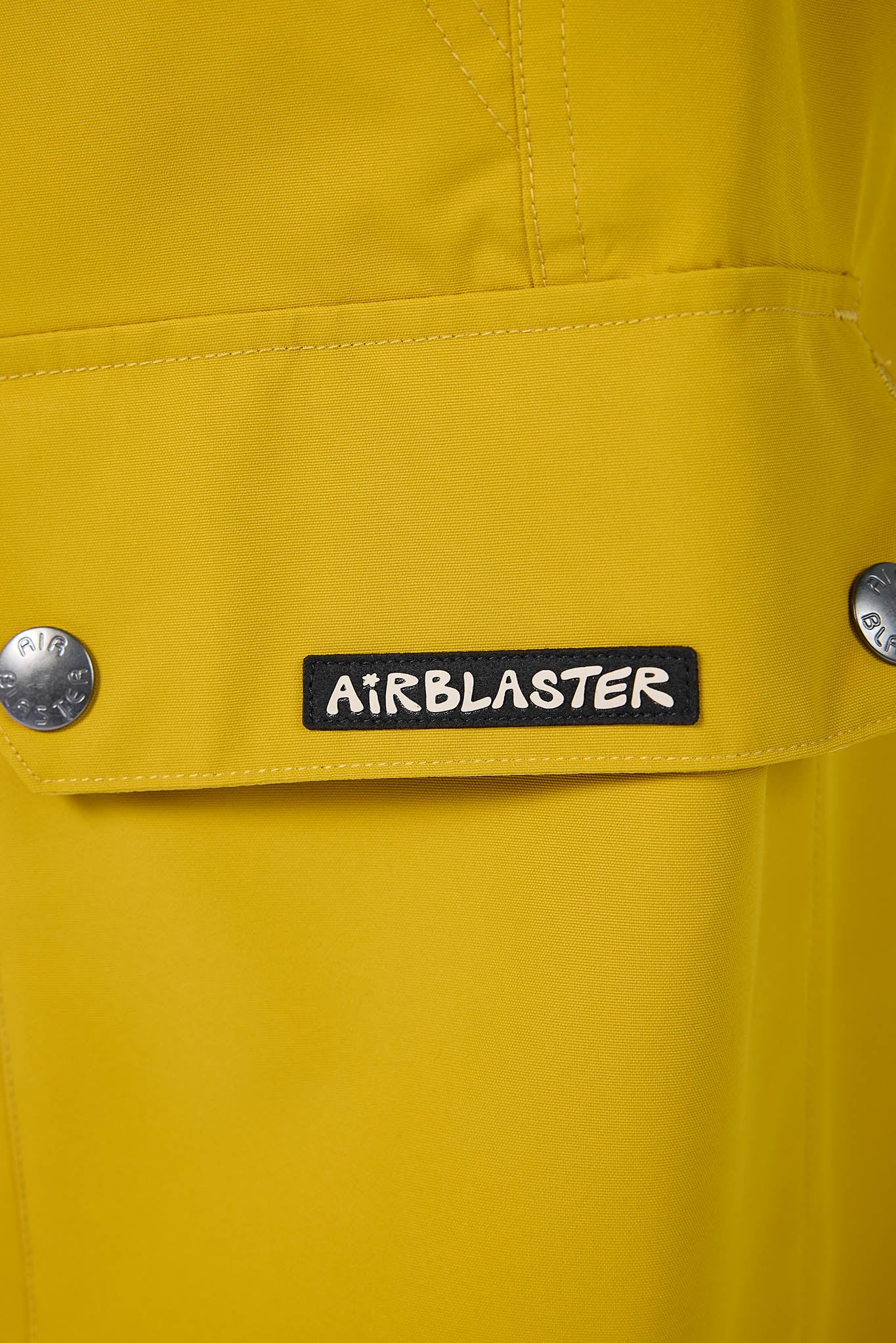 Close-up of a yellow jacket with an 'Airblaster' logo on a button.