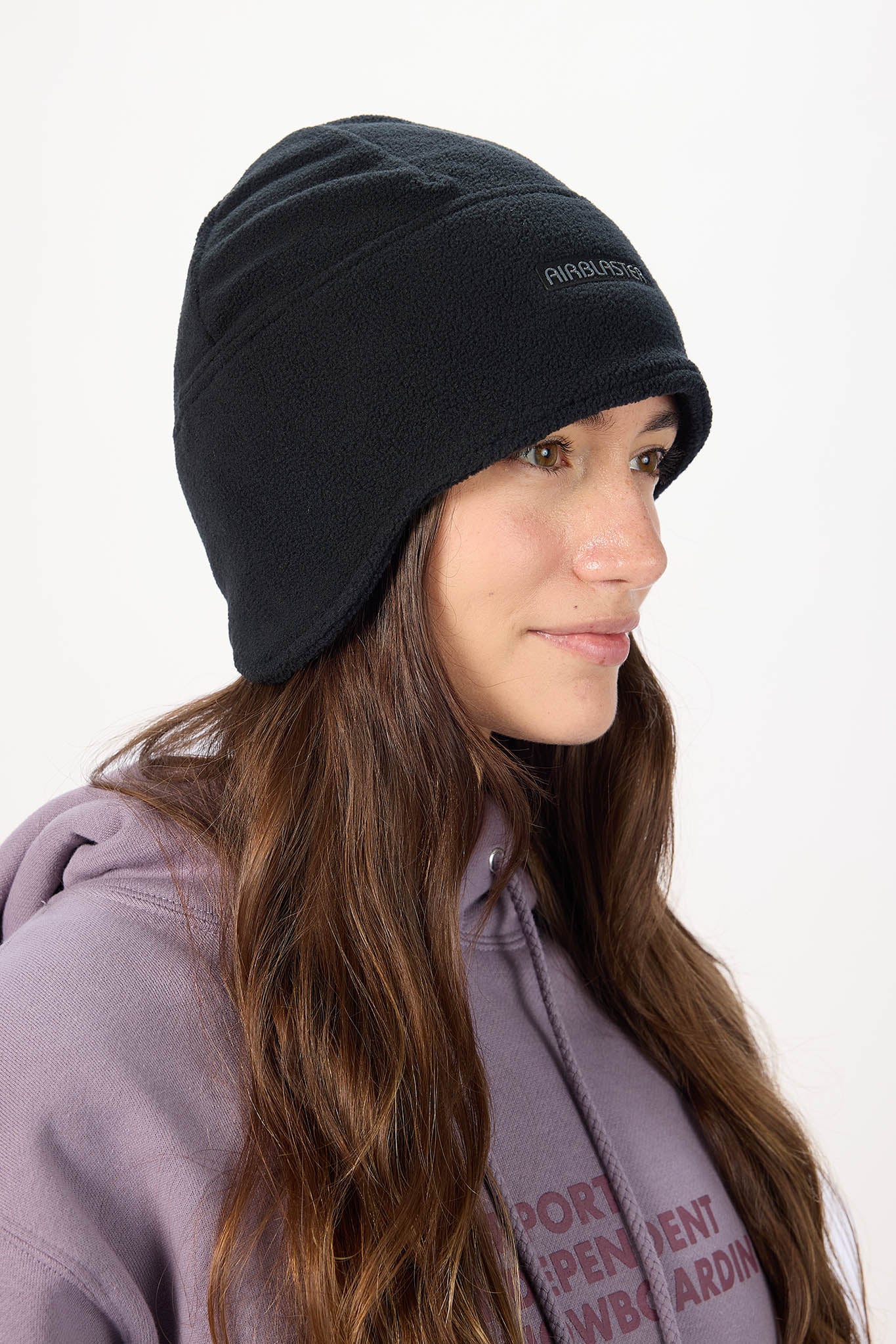 Person wearing a black beanie with a visible brand logo on a white background