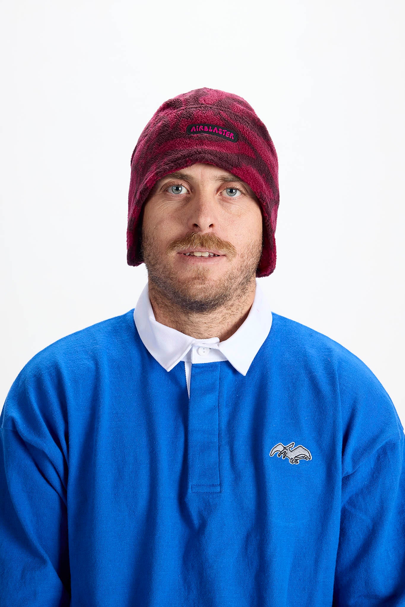 A man wearing a maroon and black patterned knit beanie