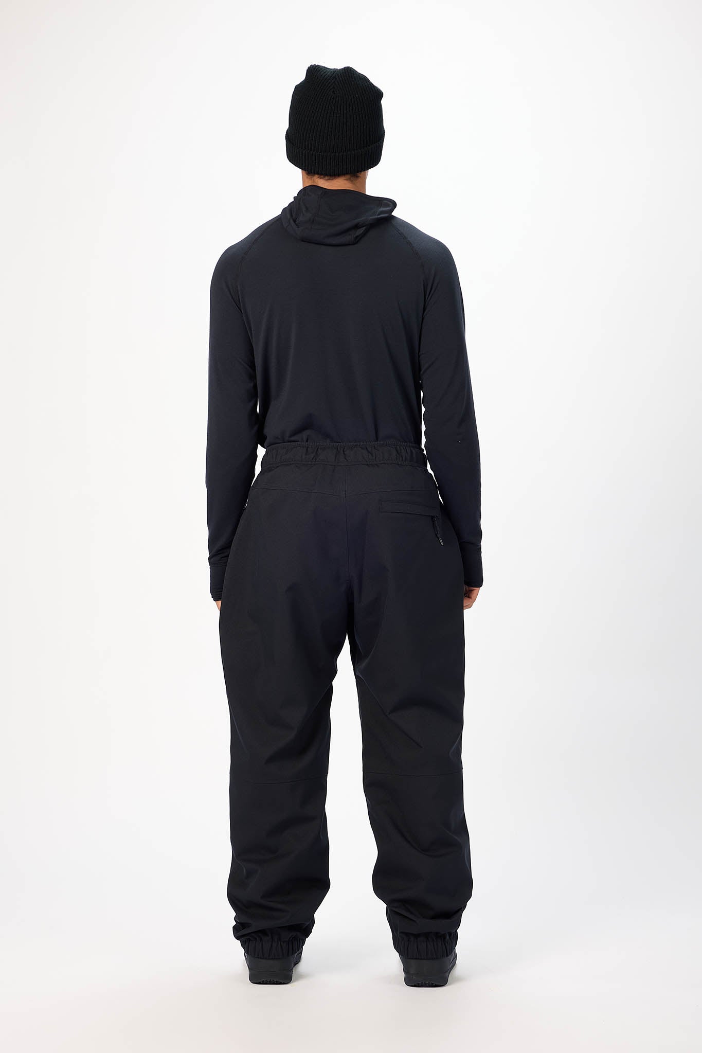 Person wearing a black hoodie and pants set on a white background