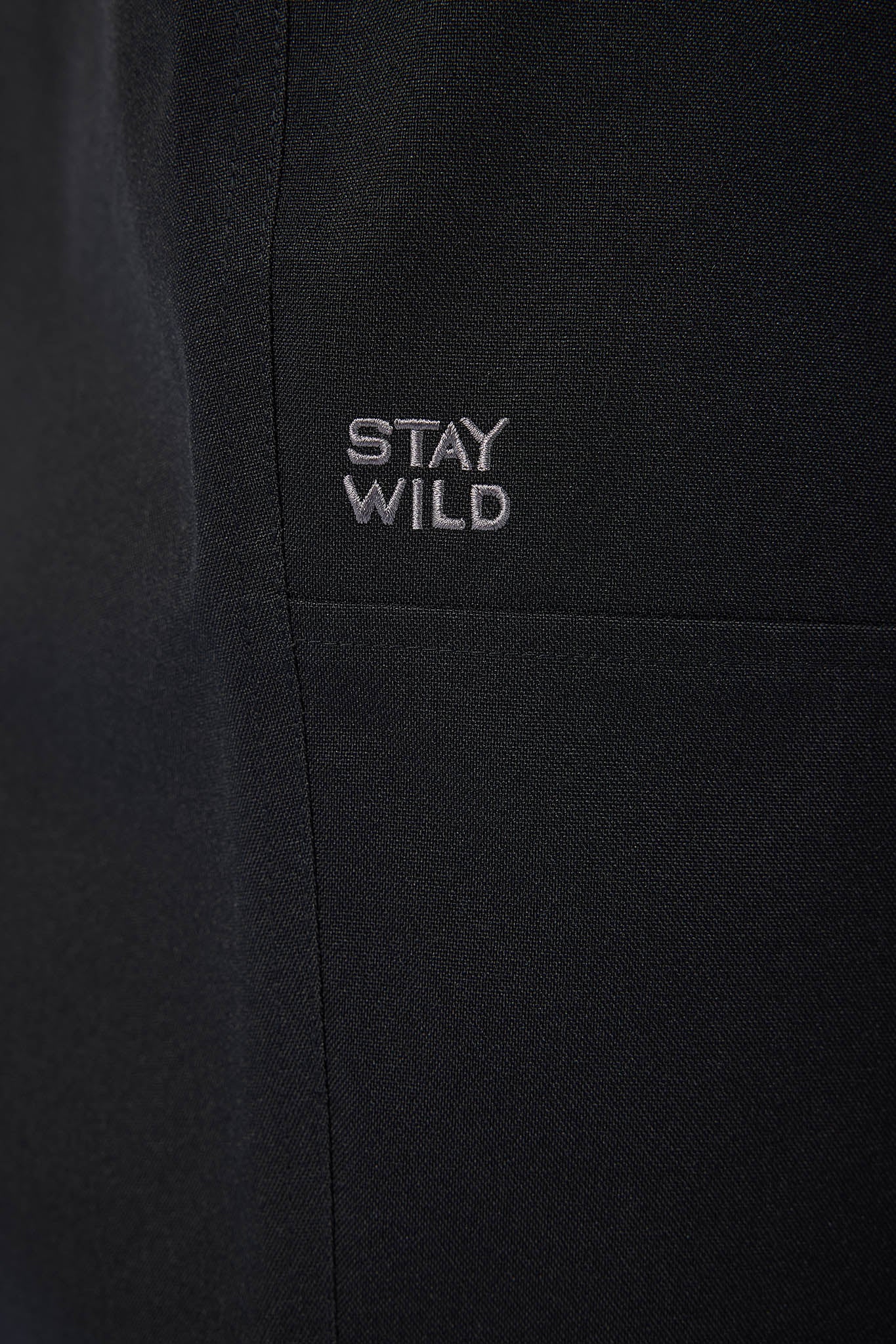 Black fabric with 'STAY WILD' text embroidered on it