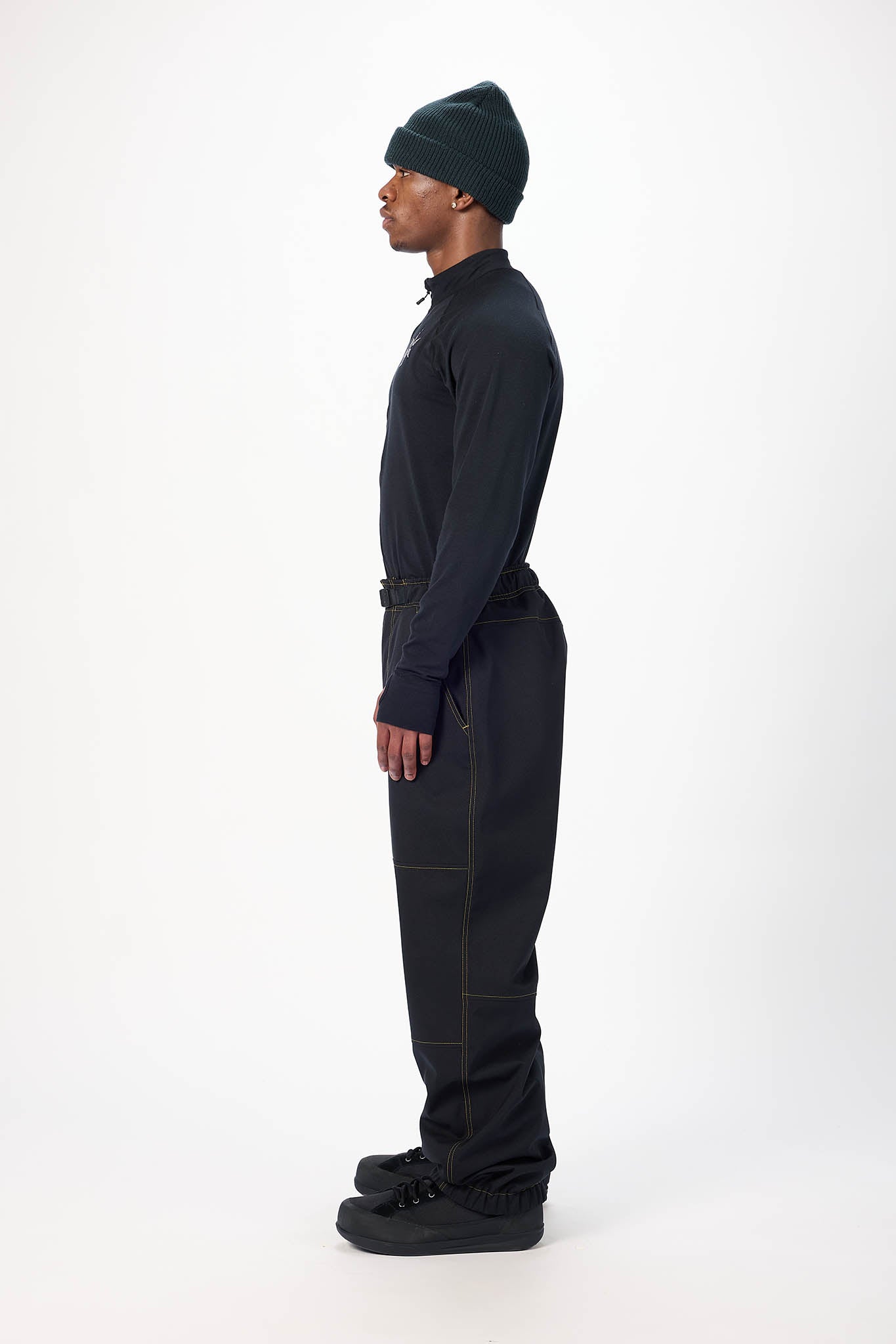 Person wearing a dark outfit with a beanie on a white background
