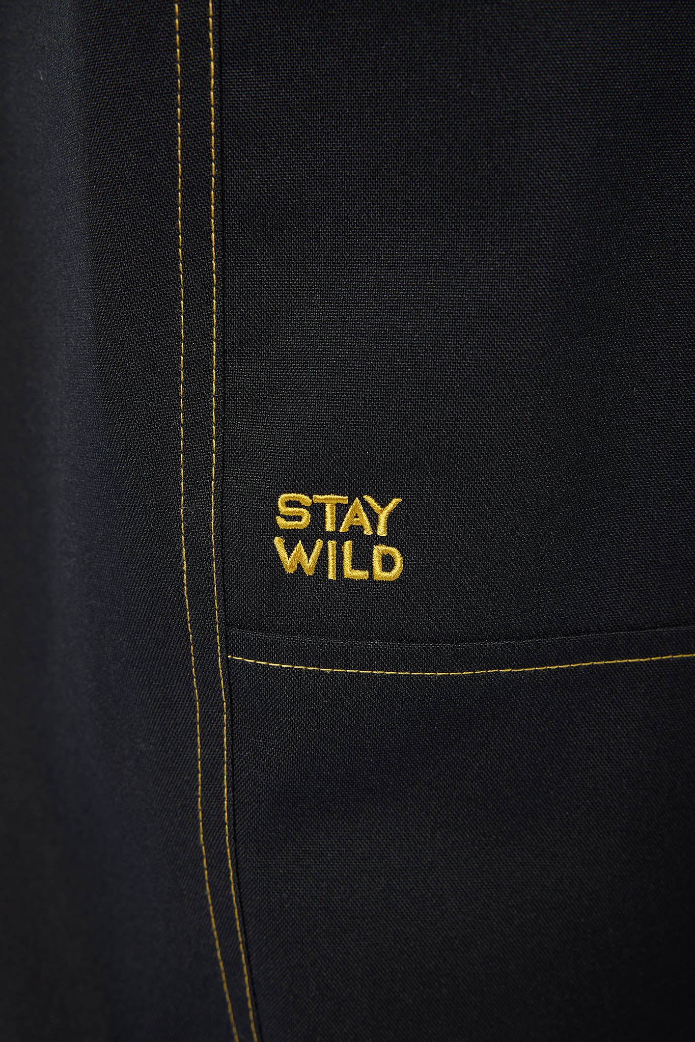Black jacket with 'Stay Wild' text in gold on a close-up view